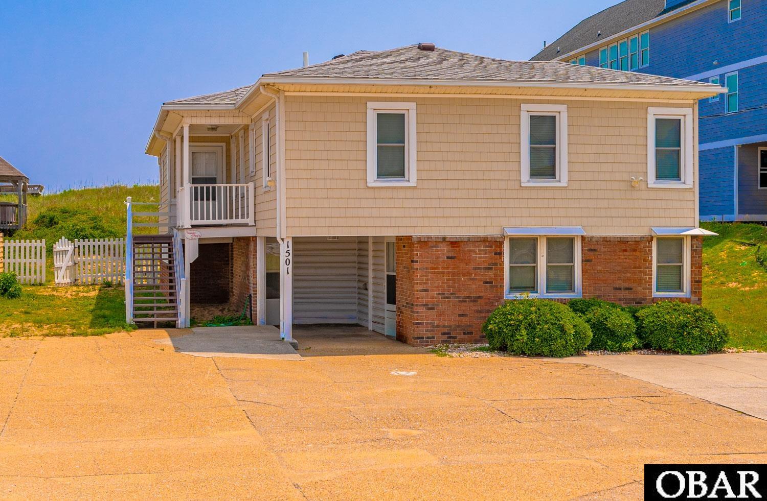 This oceanfront property has been loved by the same family for decades. It is centrally located around MP 9.5 in the heart of Kill Devil Hills. The house is set up with two living areas and has two separate entrances. Entering the upstairs is a beautiful main living area along with a kitchen, two full bathrooms and three bedrooms with one being a primary having an en suite. Conveniently located is a washer and dryer. The east side of the house has a sunroom which leads out to the deck. From there is a private walkway to the large dune deck overlooking the gorgeous ocean. But wait...there's more. The downstairs consists of another living area along with a kitchen and large eating space. There are three bedrooms, one full bathroom and an additional washer and dryer. This house sits on a 60' wide lot, and has a  90' wide, vegetated dune line.