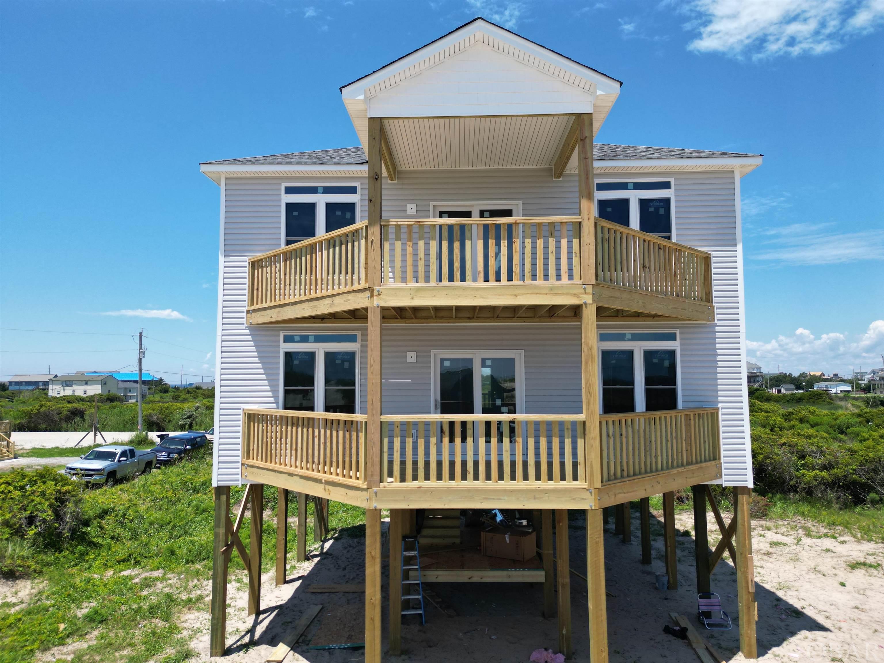 New construction with SPECTACULAR ocean views!   Estimated advertised rental income projections of $135,000 and $159,000 provided by Resort Realty and Vacasa. Located just steps from the beach in a prime water sports location close to the Rodanthe Pier. Spacious four bedroom, 4 and a half baths open concept floor plan.  First floor master suite and two additional bedrooms, full bath, bonus room and laundry.  Main level features kitchen with granite counter tops, custom tile back splash, appliances opening  into family room and a second master suite.  With over 700 square feet of deck space, expect to sit and watch beautiful sunrises and sunsets.   An additional bonus area of approximately 700 square feet of unfinished space located above flood plain.  Construction projected to be completed the end of August. You DON'T want to miss this rare opportunity to purchase a brand new home! The ocean views will truly WOW you!