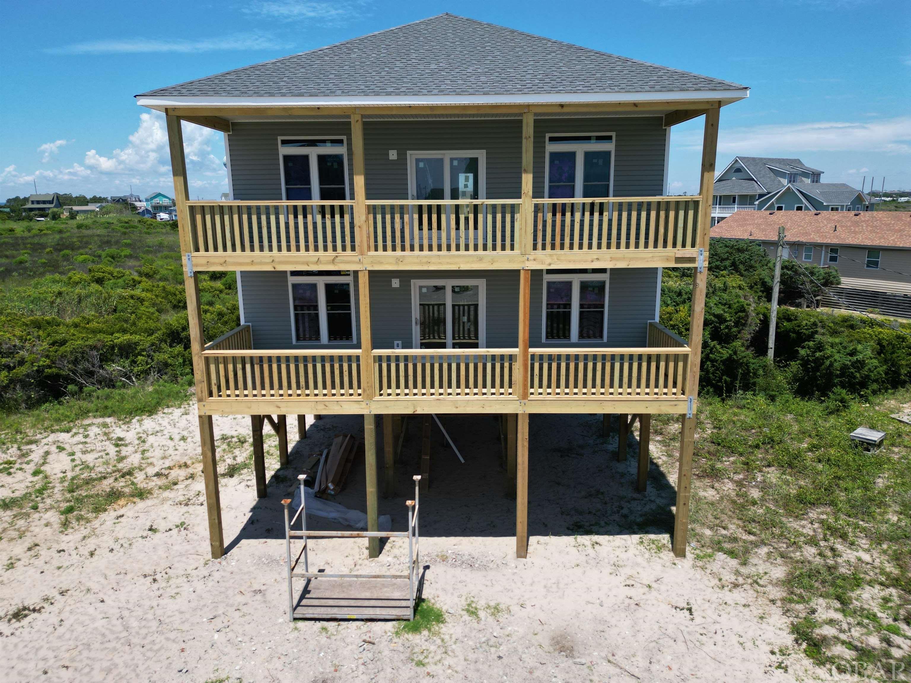 New construction with SPECTACULAR ocean views!  Estimated advertised rental income projections of $155,000 and $170,000 provided by Resort Realty and Vacasa. Located just steps from the beach in a prime water sports location close to the Rodanthe Pier! Spacious five bedroom, 4 and a half baths open concept floor plan.  First floor master suite and two additional bedrooms, full bath, bonus room and laundry. Main level features kitchen with granite counter tops, custom tile back splash, appliances opening  into family room and a second master suite.    With over 900 square feet of deck space, expect to sit and watch beautiful sunrises and sunsets.   An additional bonus of approximately 700 square feet of unfinished space located above flood plain.   Construction projected to be completed the end of September.   You DON'T want to miss this rare opportunity to purchase a brand new home!  The ocean views will truly WOW you!