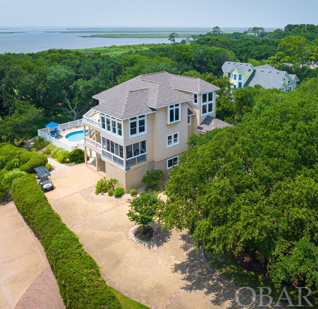 Spectacular Currituck Sound Views and Gorgeous Sunsets from Every Room! Plus Views of the fairway at the #16 hole from Every Room!  This Beautiful Updated Spacious 5 bedroom, 5 bathroom plus 1/2 bath home is located in the prestigious Currituck Club in Corolla.  Access to all 3 levels is easy with the private Elevator.  Top level features large Open Bright great room, dining room, remodeled gourmet kitchen and the largest ensuite bedroom and bath - all with fantastic Sound Views and access to the expansive top deck. Ensuite King bedroom on top level also has it's on deck access and sound views. Half bath is conveniently located between the top level and mid-level. Mid-Level boasts extensive shaded deck with additional 3 ensuite bedrooms with their own bathrooms and all with Sound Views. One King Ensuite has a screened porch to relax and enjoy the views. Second King Ensuite on the midlevel has deck access and the Twin bedroom ensuite has a sitting area plus deck access. Laundry Room with sink is also located on the mid-level. Ground Level offers the fifth bedroom with 2 sets of bunkbeds, Sound View, a hall bathroom and access to the 2 Car Garage / Game Room (881.7 Sq Ft). Awesome updated with Black/White flooring, Pool Table, Powder Shuffleboard, Foosball, Galaga Arcade Game, Ping Pong Table, Pub Table & Chairs and Refrigerator. 2 Car Garage/ Game Room has Heat and Air Conditioning. Heated Living of the Home is 3901 SqFt plus 881.7 SqFt of conditioned 2 Car Garage/ Game Room for a total of 4782 Sq Ft. The Pool area is situated perfectly to relax and enjoy the Sound views and Golf Course views from the Hot Tub and updated Pool furnishings. Some Recent Improvements include: Roof Replaced, Remodeled Quality Updated Kitchen including, Cabinets, Quartz Counters, Back Splash, new Gas Range (just converted from electric to propane), new Refrigerator, Minibar(with sink, wine cooler & Thermador Fridge Bar), Tile Plank Flooring in Kitchen and Dining room, added propane Hook Up to grill on outside top deck, Interior Painted, completely remodeled Garage/Game Room, new small fenced in area next to the pool,  Improved the view of the Sound and Sunsets with approved tree removal, new Furnishings all floors, Upgraded outdoor and Poolside Furnishings.   This home is conveniently located just steps to the Trolley stop that will take you and your family to the beach during in season at no charge. The Currituck Club is one of the few gated communities in Corolla, & offers exclusivity & an extra element of safety & security. Additionally, the Currituck Club is a prestigious neighborhood in Corolla & is the home to the Premier Reese Jones 18 hole Championship Golf Course w/ gorgeous landscaping & lots of amenities such as: Fitness Center, Pro Shop, full service Grill, several community Pools, Tennis Courts, Basketball courts, VolleyBall, Pickleball, Shuffleboard, Playground, Gated Community, Lighted Pedestrian walkways & Bike Paths, plus In Season Shuttle to the Beach.   If you are looking for an Updated beach home located Sound Front with spectacular Sound Views & Sunsets, Strong 2024 Estimated Owner Gross Rental Projection of $136,862 ( 9.44% GRI ), Private Pool, Elevator, 2 car garage/game room, & located in Flood Zone X in a quiet gorgeous neighborhood w/in season shuttle to the beach and lots of Amenities,  then this is the home for you! Sound Front Living at it's finest! Call now to schedule your appointment.