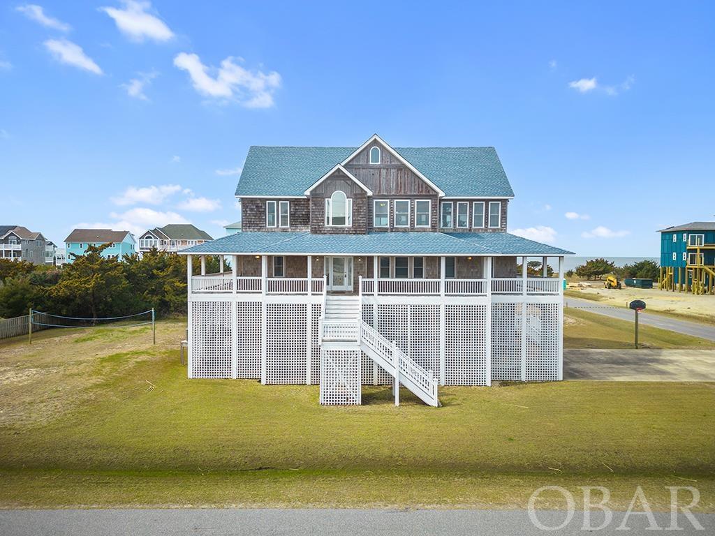 Welcome to this STUNNING, coastal, OBX-style home, located in the popular Wind Over Waves subdivision of Salvo! With this excellent location, you'll find yourself close to all the amenities a beach town has to offer! Enter into the grand foyer, with ease of access to bottom floor game room and lounge area, with full bath and bedroom. Back up to the foyer you have access to the perfect office/study currently used as TV room. Down the hall are 4 bedrooms one of which being a true master with luxurious ensuite bath. Hall bath for other bedrooms and a laundry room! Take the elevator or staircase up to the top floor where you will be greeted with beautiful sound views. Living are is large and open to spacious dining area, kitchen, and sunroom currently being used as breakfast nook. Top floor also features powder room and main primary suite with WIC, ensuite bath with soaking tub, stand alone shower, and dual vanities! All three floors have access to the convenient elevator as well as spacious decks to soak in the salt air and sun. Backyard features in ground pool, fish cleaning station, outdoor shower, hot tub, and separate entry access to the bottom floor game room. This is truly a luxury home with incredible curb appeal and design in an excellent location!