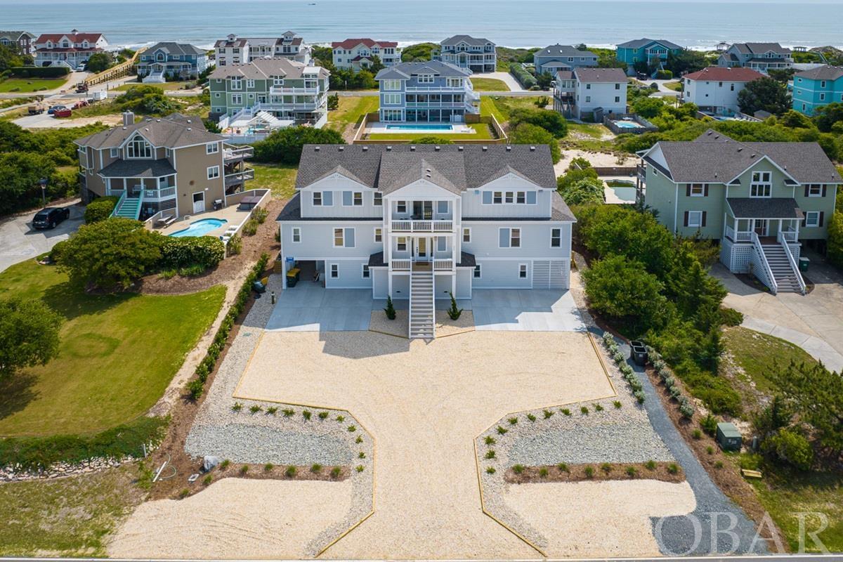 ‘Vista Mare’ is a stunning newly constructed 9 bedroom home in Corolla with spectacular ocean views and all the amenities you could imagine. A strong rental investment, this home is projected to do $286K in annual income! Located just three homes back from the oceanfront, this 5,100 sq ft custom beach house features a spacious floor plan with thoughtful and sophisticated design to optimize rental income. Enjoy convenient beach access just two doors down, making it a breeze to the beach.  VIEWS VIEWS VIEWS from the bright and airy great room on the top floor that boasts vaulted ceilings, a wall of windows, and multiple seating areas for comfort, conversation, and relaxation. Elegant and understated coastal furnishings and finishes were carefully selected to complement the clean white walls and shiplap accents. Vista Mare’s kitchen is a dream for large groups with its 6-burner gas stove and dual oven, two sinks, two dishwashers, pantry, and expansive marbled quartz island. Step outside onto the large deck off the dining area, a perfect spot to gather for cocktails, coffee, or even an al fresco meal while overlooking the Atlantic Ocean. A shuffleboard table provides added recreation in the great room, as well as a gas fireplace for use during the cooler months. The luxurious top floor master bedroom offers its own private deck and an ensuite bathroom with double vanity. Enjoy an elevator to take you to each of the three levels with ease.  Six additional ensuite bedrooms can be found on the mid-level, each with a private bathroom. The bedrooms offer a variety of bed arrangements to accommodate families and groups, including a custom-built 6 bed bunk room and a family suite with 2 queens, a vanity room, and a shower with tub. With added features like a custom coffee bar on the mid-level with a sink and full-sized fridge, this home is built to offer convenience and elegance. Downstairs you’ll find the remaining two bedrooms that share a full bathroom and a covered deck overlooking the serene pool area. Entertainment abounds on the ground floor with a well-equipped rec room with pool table, walk-behind wet bar with fridge, and a theater room with barn doors and two-tiered lounge seating. Enjoy a ping pong table, putting green, cornhole and bocce, and hot tub around the pool complex where you’ll also find the same luxurious coastal aesthetic as inside the home. Designed for relaxation, there is a built in shallow sundeck in the pool, and a poolside cabana that provides a perfect place for guests to watch TV and take a break from the sun. The home features multiple technology upgrades, including smart TVs, and a Sonos audio system throughout the interior and exterior. Conveniently located in the Whalehead subdivision, just a bike ride or short drive to the best shopping, dining, and entertainment in Corolla.