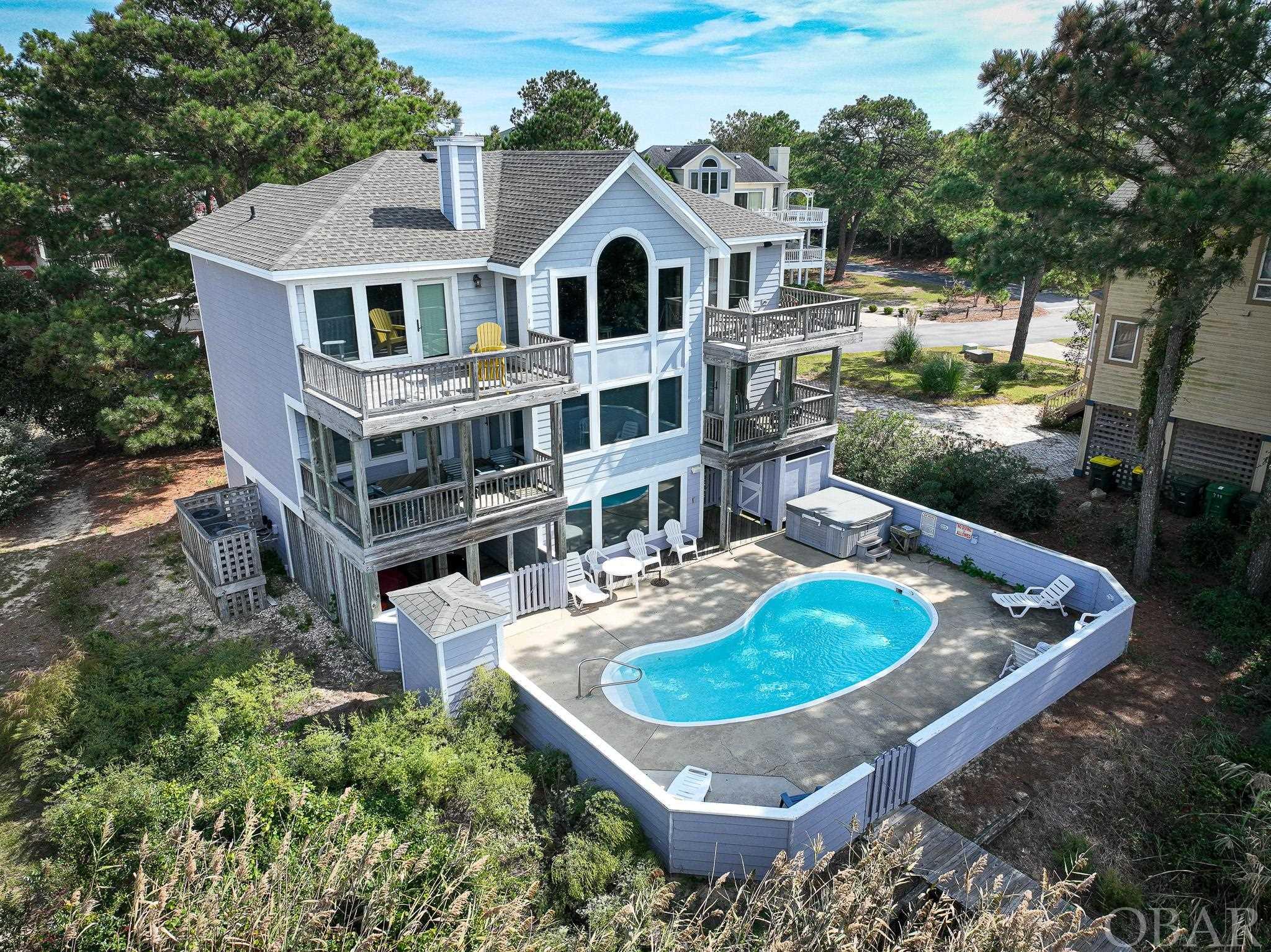 Welcome to 876 Drifting Sands Drive, where the beauty of coastal living meets the tranquility of Soundfront serenity. This luxurious home offers a generous heated living space, boasting five bedrooms, five and one-half baths, a game room, an elevator, a sparkling in-ground pool, and a private boardwalk leading to the breathtaking Currituck Sound.  Here are the remarkable details:  Nestled along the tranquil shores of the Currituck Sound, this home provides a front-row seat to mesmerizing sunsets, gentle breezes, abundant wildlife and the serene beauty of the Outer Banks.  With over 3,000 square feet of living space, this home exudes a sense of space and luxury. The open floor plan allows for easy living and entertaining, while large windows frame the captivating water views. Five Luxurious Bedrooms: Each bedroom is designed with comfort and relaxation in mind. Wake up to the soothing sound of lapping waves and enjoy private en-suite bathrooms.  Endless Entertaining Possibilities: The game room is the perfect space for indoor entertainment, featuring a fosse ball table and ample room for family and friends to gather. Whether you're hosting a game night or a movie night, this area offers endless possibilities.  An elevator makes it easy to access all levels of this stately home, ensuring accessibility and convenience for all family members and guests.  Step into the backyard and discover your own private paradise. The in-ground pool is perfect for cooling off on those warm summer days, and the surrounding deck is ideal for lounging in the sun.  Meander down your private boardwalk leading to the sound. This is your gateway to activities like kayaking, paddle boarding, fishing, or simply relaxing by the water's edge.  Corolla is known for its peaceful, upscale community and pristine beaches. You'll be close to local shops, restaurants, and the famous Corolla Wild Horse Tours.  Don't miss the breathtaking sunsets that grace the Currituck Sound every evening. Whether you're sipping a glass of wine on the deck or enjoying dinner with family, each sunset will be a memory to cherish. Experience the epitome of coastal living at 876 Drifting Sands Drive. This Soundfront oasis offers the perfect blend of luxury, comfort, and natural beauty.    This home is not only a stunning retreat but also a fantastic investment opportunity. Soundfront properties are highly sought after for vacation rentals, making this an excellent income-producing property.  Contact us today to schedule a viewing and make this dream home yours!