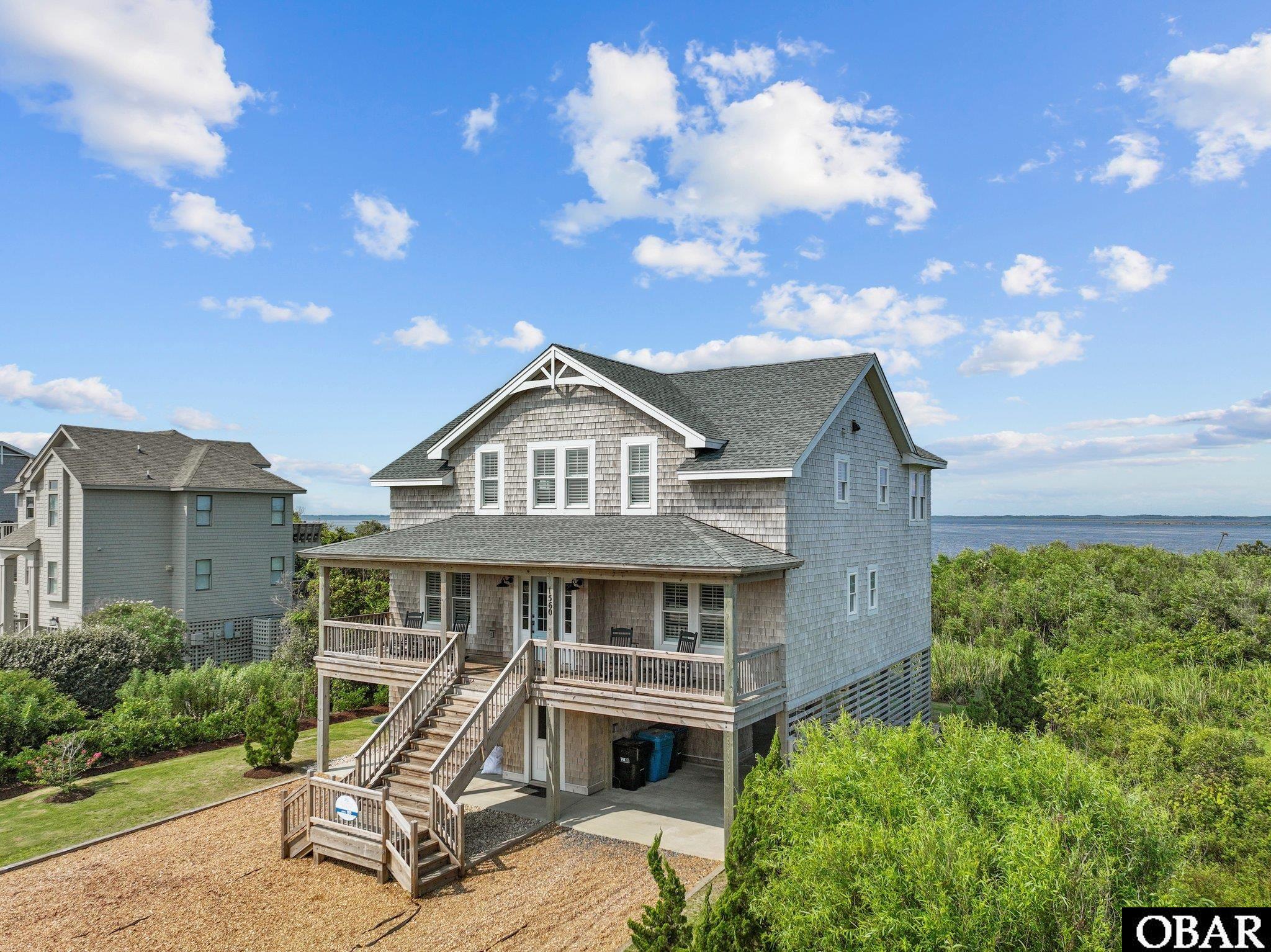 This stunning five-bedroom, four full, and one-half-bathroom waterfront property is a true gem, flawlessly integrating breathtaking sound views and masterful construction to offer the ideal balance of formal and serene seaside living. This beautiful soundfront home in the sought-after town of Duck represents an excellent opportunity to buy an investment property, second home, or primary residence. This luxurious and top-tier property was built in 2019 by renowned Renaissance Construction and has over 2450 square feet of exceptional craftsmanship.  The exterior features a landscaped yard with a walkway to a private dock with bench seating, an enclosed one-car garage, a carport area, and two covered porches, which provide excellent locations for leisure and for taking in the breathtaking views.  A third deck space enables sunning while enjoying the refreshing waterfront breezes.  The interior is similarly impressive. The elevator provides convenient access to each level including the garage.  The well-equipped kitchen easily connects to the inviting living room, producing a warm and friendly environment for informal living and gatherings with plenty of natural lighting. The gas fireplace along with built-in benches in the living area add an extra touch of warmth. A formal dining room with breathtaking views adds a sense of refinement to the kitchen and living space.  The five bedrooms and four full bathrooms that have custom tile and glass showers ensure privacy and comfort for you and your guests.  This savvy arrangement also offers excellent rental potential, making it an appealing financial decision. Other features worth noting are solid panel doors, plantation shutters, auto light closets, a tankless water heater, and plenty of storage, both inside and out. As part of the desirable Sanderling Community, more specifically Station Bay Cove, this property provides convenient access to various amenities and fantastic restaurants.  Experience the conveniences of modern coastal living while indulging in the charm and tranquility that Duck has to offer.  This remarkable waterfront escape embodies elegance, comfort, and the essence of coastal living! Please be sure to check out the virtual tour of this property by copy/paste into your browser: https://my.matterport.com/show/?m=LCMxNL4yatH&mls=1