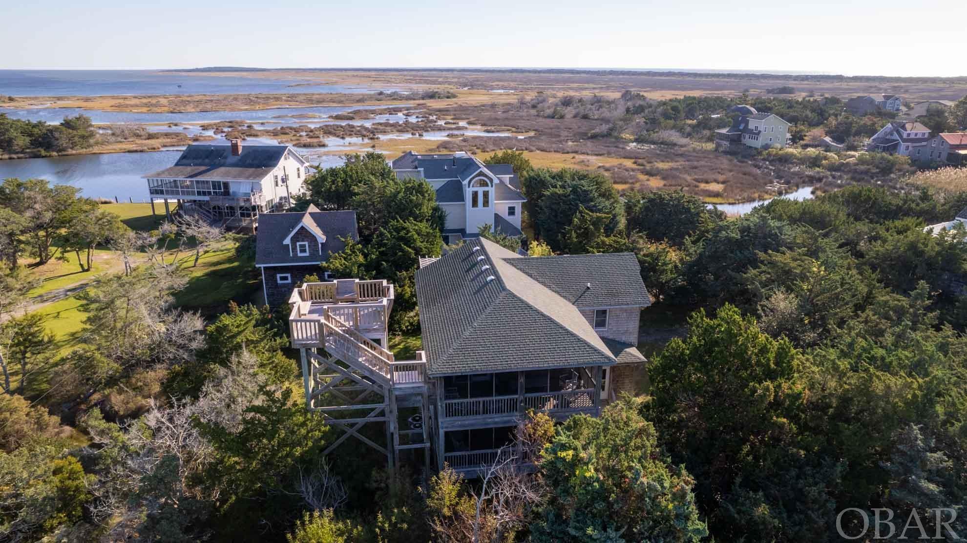 This beautiful custom built home is just one house down from end of a dead-end road with a foot path to canal connecting to Pamlico Sound providing kayak, SUP or john boat access to all residents of Sarah Ellen. Artfully designed, the reverse floor plan offers privacy and excellent natural lighting.  Multi level decks and screened porches capitalize on the tranquil setting.  A roof top deck with built in seating offers panoramic views from sound to ocean.  The first floor has 3 bedrooms and a full bath, washer dryer, an office/study/bonus room and a large room with its own exterior door access which could be used as an additional bedroom (septic system can accommodate up to 4 bedrooms).  The second floor has an open floor plan and cathedral ceilings with a spacious kitchen open to a dining and living area and a 1/2 bath.  Also on this floor is master bedroom with its own custom tiled bath.  A large, full house length 2 level screened porch runs along the back of the house, two level open decks adorn the front.  On the north side the large roof top deck boasts spectacular views and sunsets.  This home is currently seller's primary residence but could easily become a spectacular vacation rental providing supplemental income.