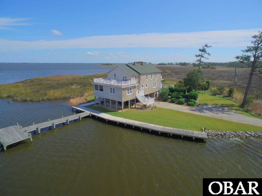 Welcome to Sawyer’s Lodge!  This charming, historic cottage nestled in the heart of the picturesque, coastal countryside of Currituck County, offers a truly unique opportunity to embrace a serene and comfortable lifestyle. Originally built in the 1920’s and known as the G.C. Sawyer Hunting and Fishing Lodge, it was lovingly and faithfully restored to its current condition with modern conveniences about a decade ago.  Located on its own private peninsula, this waterfront retreat feels like your very own private compound. With its prime location just a few miles away from all the conveniences of the beach, yet surrounded by the tranquility of nature, Sawyer’s Lodge is a perfect blend of modern, coastal living and rural charm.  Sitting on a .62-acre lot that seems infinitely larger, this property provides ample opportunity for numerous outdoor activities.  Revel in the breathtaking vistas of the surrounding marsh and the Currituck Sound and imagine waking up to the soft hues of sunrise and unwinding to the captivating colors of sunset. Original details such as hardwood floors and bead board walls are still intact, yet blend seamlessly with the updated kitchen and bathrooms.  The bedrooms offer a peaceful haven, and each provide comfort, privacy, and spectacular views. The master suite includes an en suite bathroom for your convenience and a private deck with stunning panoramas.  In addition, there are two family living areas as well as a dining room, and a fantastic screened in porch!  The private swimming pool and hot tub are surrounded by water views and only stars light up this sky at night. There is an adjacent boat launch and brand new private, platform dock for your boat and other water toys! In addition to the beach, Sawyer’s Lodge is just minutes from H2OBX Water Park, The Point Golf Club, Kilmarlic Golf Club, and Buffalo City Distillery.  You must see it in person to understand the breathtaking beauty this waterfront property offers.  Don't miss out on the opportunity to make this charming countryside retreat your own! Whether you're seeking a year-round residence or a weekend escape, Sawyer’s Lodge promises a lifestyle of comfort, tranquility, and beauty.