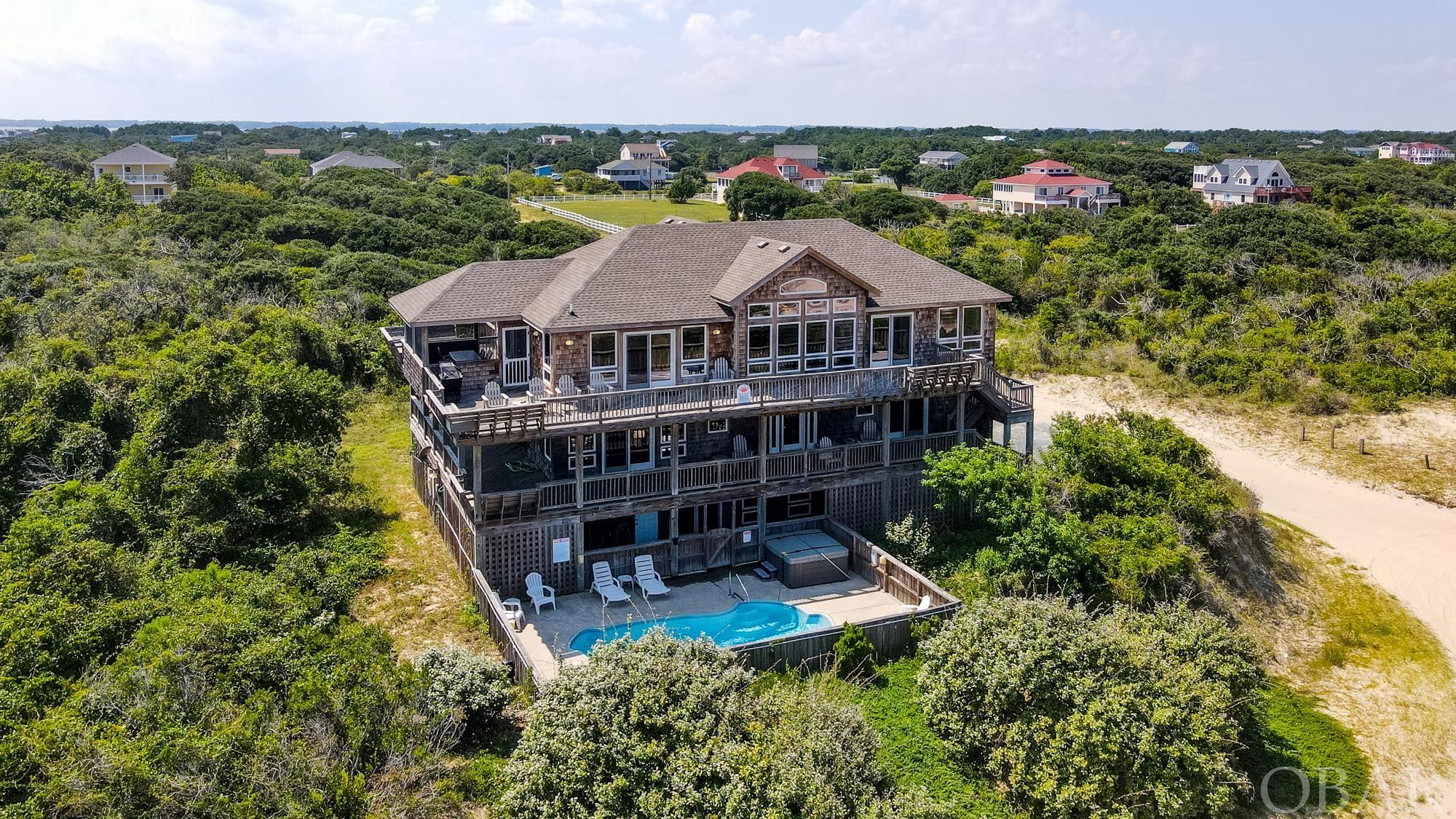 This semi-oceanfront home has everything that you look for in a great beach house in Carova.  The home sits on an elevated ridge with great ocean views and with no flood insurance required.  Right under 4,500 sq/ft, this house has a great layout with large bedrooms, custom finishes and a huge rec room that leads out to the ocean facing pool.   All six bedrooms have their own private bathroom and most lead out to decks where you can enjoy ocean views and wild horses roaming.  The third level great room is filled with natural light and a wall of windows on the east side of the house.  This area also comes equipped with Brazilian cherry hardwood floors, granite countertops and a large kitchen that any chef would desire.  New roof this past year, projected to do $146,090 in gross rents for 2024, this house makes for a great rental investment.