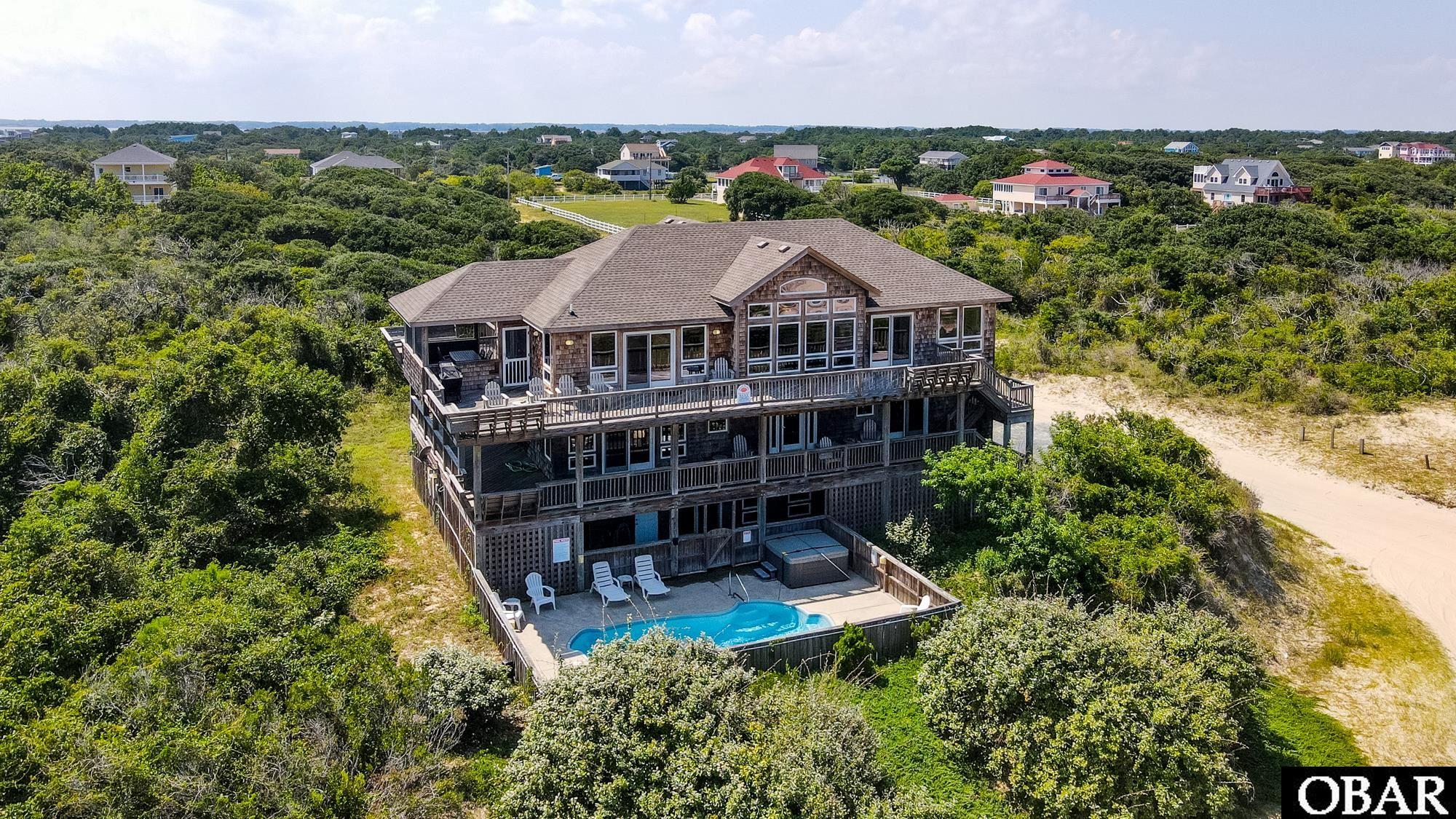 This semi-oceanfront home has everything that you look for in a great beach house in Carova.  The home sits on an elevated ridge with great ocean views and with no flood insurance required.  Right under 4,500 sq/ft, this house has a great layout with large bedrooms, custom finishes and a huge rec room that leads out to the ocean facing pool.   All six bedrooms have their own private bathroom and most lead out to decks where you can enjoy ocean views and wild horses roaming.  The third level great room is filled with natural light and a wall of windows on the east side of the house.  This area also comes equipped with Brazilian cherry hardwood floors, granite countertops and a large kitchen that any chef would desire.  New roof this past year, projected to do $146,090 in gross rents for 2024, this house makes for a great rental investment.