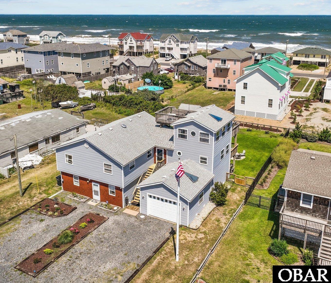 Bright and light with ocean views from decks and many rooms in the home.  Recently installed ELEVATOR and many updates including rear deck, security system, flooring, paint, irrigation and more. A complete list is available upon request.  Top level  is spacious and features three bedrooms, an extra room, three bathrooms, kitchen, great room and deck access. The third floor ship's watch is currently used as an office with ocean views and access to the exterior crows nest for enjoying sunrise and sunset. A large lower level apartment features two bedrooms, one bathroom, kitchen, living room and dining area. The apartment was recently renovated including a new bathroom, flooring, paint and trim. 680 sq. ft. garage with additional side workshop area. The rear yard is fenced and beautifully landscaped with irrigation. Roof 2013 per previous owner. New upstairs HVAC 2023. This Legal Duplex in Kitty Hawk with two separate meters.