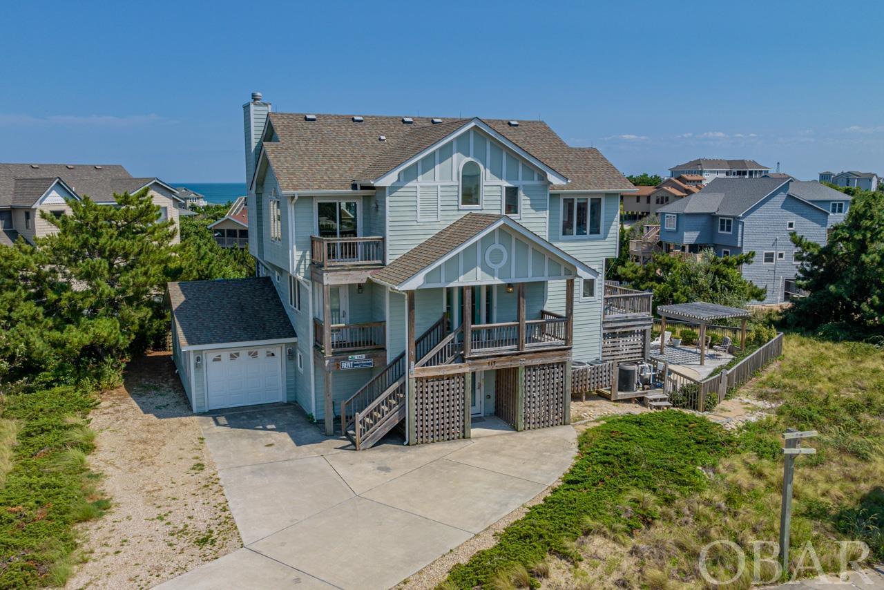 Discover coastal elegance and endless comfort in this exquisite 5-bedroom, 4.5-bathroom home located in the charming town of Duck. Ideally situated just a short stroll from the neighborhood beach access, this residence offers both breathtaking ocean and sound views, creating a captivating backdrop for your Outer Banks lifestyle. The ground level of this well-designed home welcomes you with a thoughtfully appointed layout. On this level, you'll find a convenient bedroom and full bathroom, a spacious den complete with a wet bar, and an elevator granting access to all floors. The large office is a haven of productivity, and the added bonus of garage access enhances the convenience. The laundry room is also located on this level. Ascend to the second floor, where comfort and convenience continue to shine. Three bedrooms, two of which feature private bathrooms, provide ample accommodations for family and guests. Access to the covered deck offers a serene spot to unwind and take in the surroundings. The third floor/top level is a true masterpiece of coastal living. Elevated ocean views greet you, creating an ever-changing panorama. The sun deck invites you to bask in the warmth of the sun and enjoy the sea breeze. Inside, the living room, dining room, and kitchen harmoniously blend into an open space that exudes both elegance and functionality. Granite countertops and stainless steel appliances in the kitchen elevate your culinary experience - along with a large pantry. A sun deck with captivating sound views complements this level, providing an idyllic spot for relaxation.  Located on this level is 1 additional bedroom with private bathroom and access to an ocean facing office. There is also a 1/2 bathroom located on this floor. Venture outdoors to discover a private pool, inviting hot tub, and a spacious pool deck adorned with a shaded pergola – perfect for outdoor gatherings. The playground adds an element of family fun. The Carolina Dunes neighborhood offers not just one, but three beach accesses, ensuring easy enjoyment of the coastal wonders. Additionally, community sound access enhances the allure of this sought-after location. Embrace the close proximity to the picturesque town of Duck, where multi-use paths for walking, running, or biking, charming restaurants, a boardwalk on the sound, and a plethora of family-friendly activities await. Your dreams of coastal living are realized at this exceptional Duck retreat.