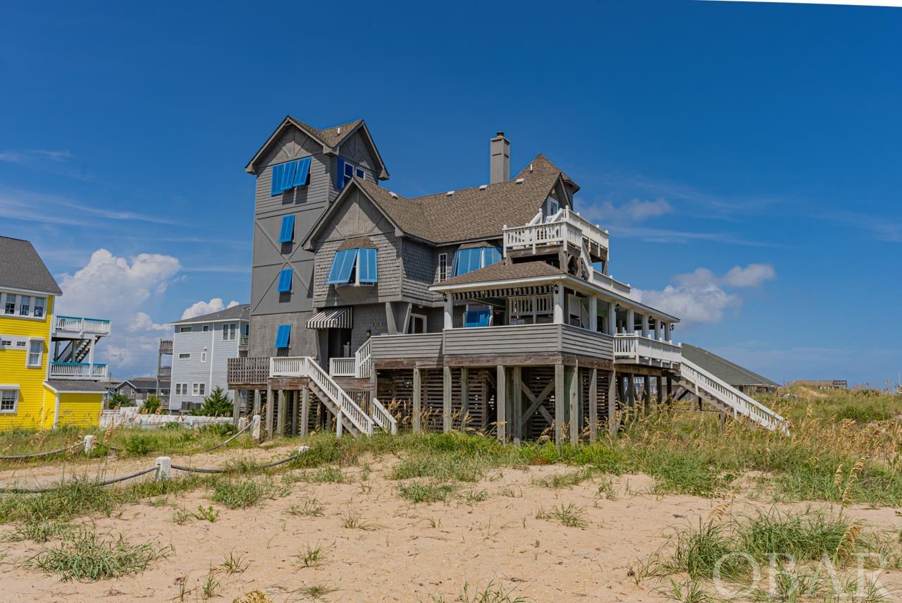 Oceanfront in Rodanthe — Immortalized in “Nights in Rodanthe”. Imagine living the scenes of your favorite movie at the iconic INN AT RODANTHE, the very same setting that captured hearts in the film “Nights in Rodanthe” starring Richard Gere and Diane Lane. This home is more than just a backdrop; it's a real-life cinematic masterpiece, beckoning you to experience your own enchanting story. While the ocean's embrace no longer surrounds the home's pilings (it was relocated to safeguard against future storms), this six-bedroom, four-and-a-half-bathroom residence still graces an awe-inspiring oceanfront perch. Multiple levels of outdoor decks offer breathtaking views that the characters themselves would envy. Enter the first level via staircases on either side, where a cozy living room, a charming kitchen, and a dining area await. Original movie set pieces, like the artistic swinging kitchen doors, are seamlessly integrated into the home's decor, capturing the magic of the film. The first level also boasts a wet bar, a full bath, and a convenient laundry area. The second level is home to four bedrooms, including the renowned antique-filled blue bedroom, reminiscent of Paul Flanner's quarters in the film. Another room features twin beds, evoking Adrienne's cherished memories of her father. A king master bedroom overlooks the ocean, and a garden room with a queen bed provides serenity. The third level boasts a king bedroom with a kitchenette and sitting area, a haven of seclusion with ocean vistas. The crowning jewel is the tower bedroom, a king suite that offers endless ocean views. While the home's decks witnessed dramatic scenes in the movie, they now offer endless moments of relaxation. Unwind with a book in a rocker or indulge in the hot tub on the lower deck, serenaded by the waves. A screened-in porch offers sheltered outdoor living. Nearby, you'll discover other filming locations to explore, but nothing rivals the private beach stretching before the house. Just like the characters in the film, embrace the concept of second chances as you create your own memorable story. Don't miss out on this extraordinary offering to own your piece of history and make your own lasting memories by the sea.