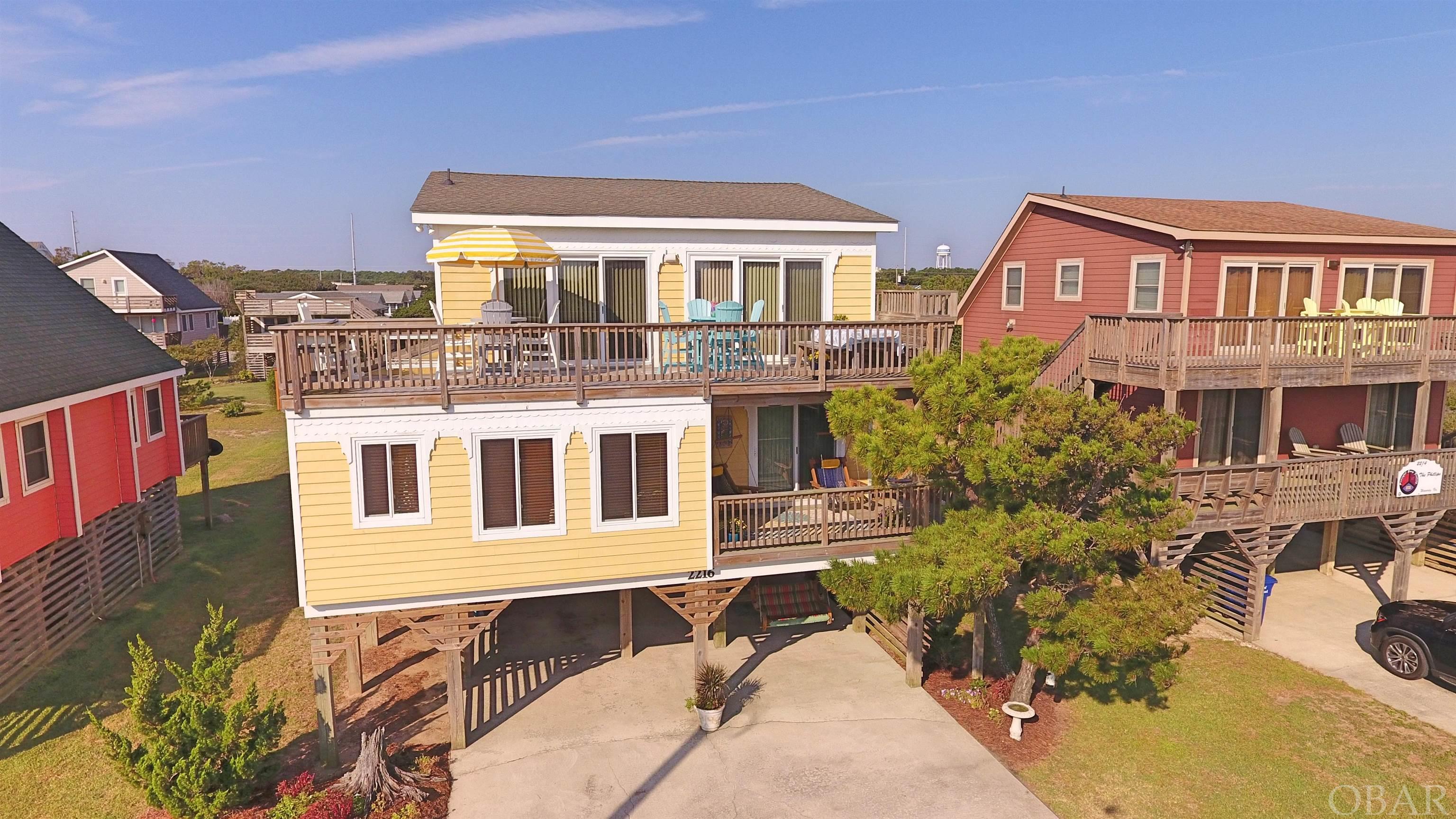 Over-the-top upgrades makes this the WINNER.  All the charm of a beach cottage with improvements suited for year round living!  This home has exceptional ocean views and is centrally located near shopping, dining, and of course, the beach!  The Owners have transformed it to a seasonal primary home for the summer months.  The reverse floor plan allows panoramic views from the main living area.  The expanded sun deck runs the length of the home and features durable wood composite furnishings.  Rich custom cabinetry, Silestone counters & backsplash, and GE stainless appliances grace the fully remodeled kitchen.  Hardwood flooring runs throughout the home, with distinctive ceramic tile in baths and kitchen/dining area.  Attic space has been converted to expand the living area with an attractive reading nook and bonus room off of the powder room.  Head down a flight of stairs, where all four bedrooms are located.  The primary suite was expanded in 2016 to include a sumptuous floor-to-ceiling marble walk-in shower, custom dual sink vanity and pendant lights, and upscale oiled bronze fixtures.  The personalized walk-in closet keeps everything in easy reach.  A slider door opens to the cheerful  covered deck, complete with Nags Head Hammock swings and a gate to keep pets by your side.  The second bedroom also opens to the covered deck and accesses a Jack and Jill bath between the two easterly bedrooms.  Two additional bedrooms on the west side also share a common bath.  Of course, the Outer Banks is all about outdoor enjoyment, and this home features a sunny ground level patio, breezy carport with swing and picnic table and an inviting outside shower. The ground level storage room houses washer, dryer, and a separate lockable room with second refrigerator.  Quality furnishings convey with just a few exclusions.  The owners have been fastidious caretakers, with all new exterior decking & stairs, new roof, new cedar lap siding, new plumbing, new HVAC, new hurricane impact windows and doors in the last 10 years.  Rental projection on file for over $65K, add a pool for almost $80K!   Ask for a complete list of improvements.