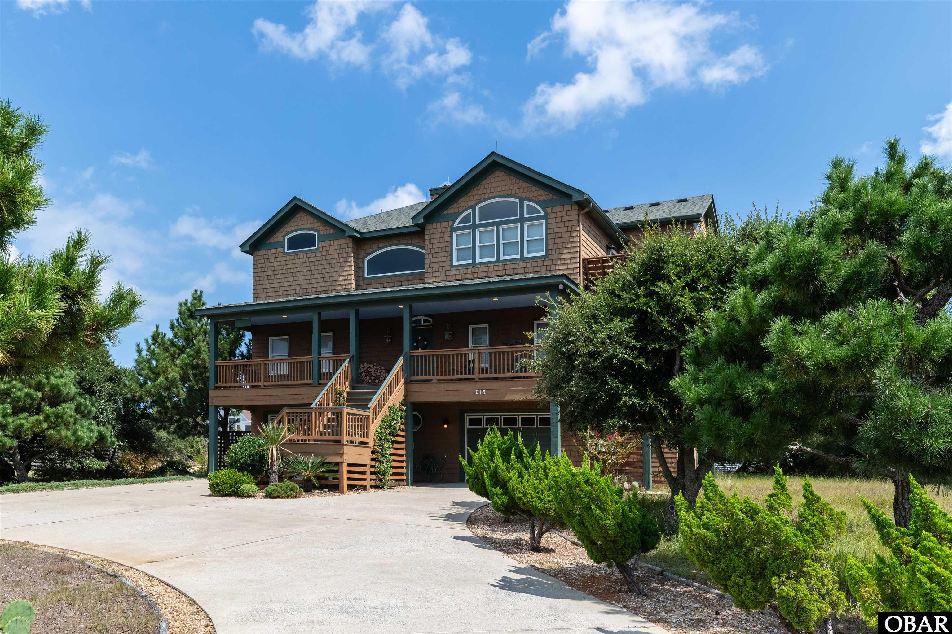 Exceptional 3rd-row location with outstanding ocean views!  Only steps to the pristine beaches of Whalehead. This nicely elevated property sits next to a community easement, providing privacy and excellent curb appeal.  Built by Beach Realty as a primary residence and lovingly cared for by the owner occupant. The ground level features an ensuite with access to the backyard.  Also on the ground level are two generous garages and a large, finished storage room that can be used for various purposes.  The mid-level foyer features cathedral ceilings and opens to the game room area.  Also on the mid-level is the 2nd of 3 ensuites and two more bedrooms that share a full bathroom.  The separate laundry room is also on the mid-level.  On the top level, the open-concept great room features a beautiful stone fireplace and ocean views.  The abundant natural light lends itself to the bright, relaxed feel.  The kitchen offers a peak at the Corolla lighthouse.  The top-level ensuite features his and her closets and a soaking tub.  As a former primary residence, this home has features you rarely see, such as gutters, lightning rods, and more storage than the typical beach house.  The quality of construction is evident throughout the home.  HVAC units are five years old.  All window screens are stored in the garage.  Ethan Allen wood furniture does not stay with the house.