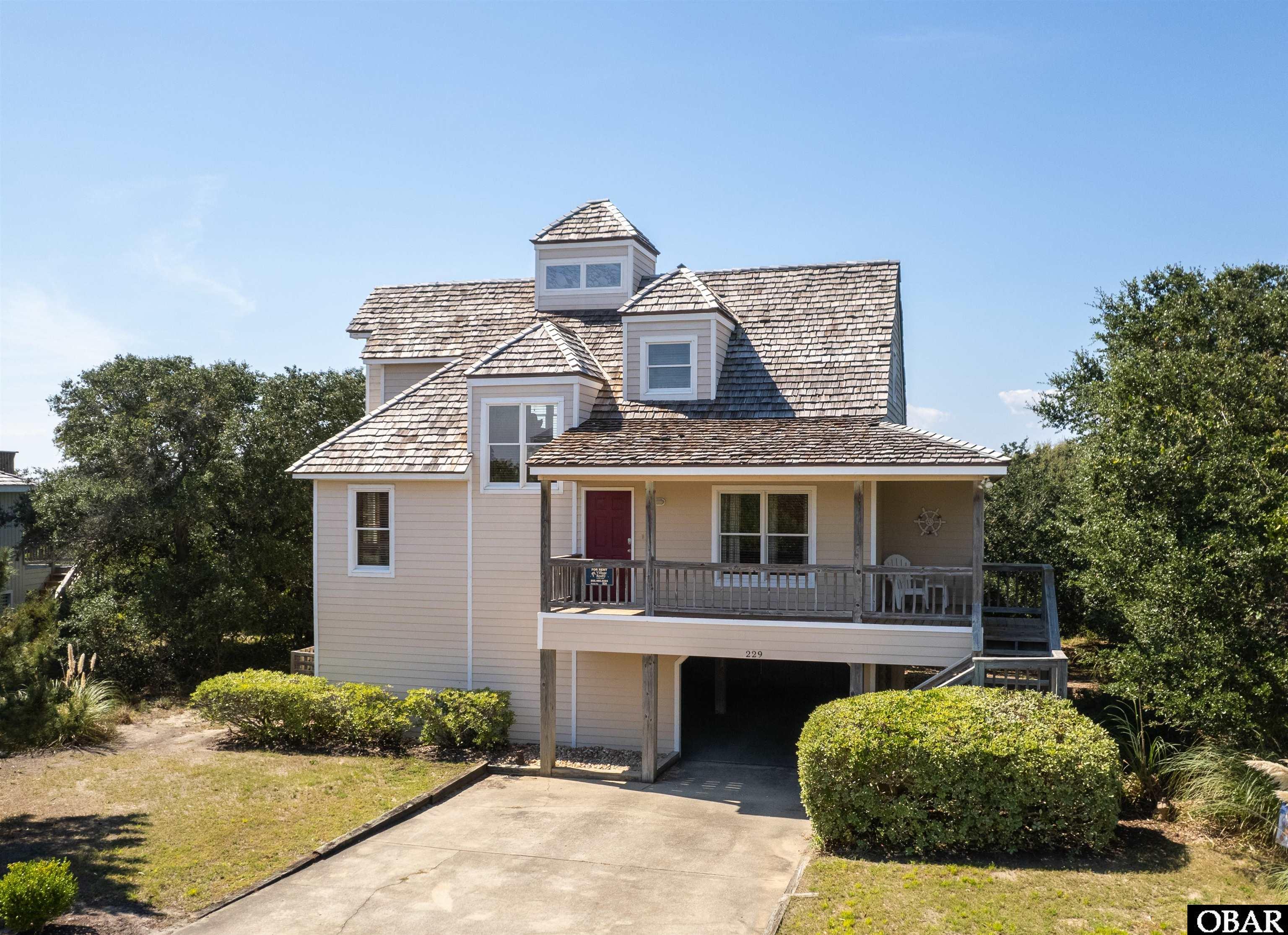REDUCED PRICE! Beautiful Sound Views through the trees and across the Nags Head Golf Links. Enter the home on the mid level. Reverse floor plan offers maximum water views from great room. This area features an upgraded kitchen with a flat cooktop, a built-in microwave, and a wall oven. A cupola in middle of the room offers natural lighting that brightens the space during the day. Mid level has a large primary, en suite bedroom and a second primary, also with a private bath. Two other bedrooms share a hall bath. A washer and dryer are conveniently located in a half bath. Ground level has a carport, one storage room, and a workshop with a second refrigerator. Seller had new FORTIFIED cedar shake roof installed in 2020 and all polybutylene plumbing replaced with pex in 2019. Memberships are available in the semi-private, 18 hole links golf course, and the private Village Beach and Tennis Club on the oceanfront.