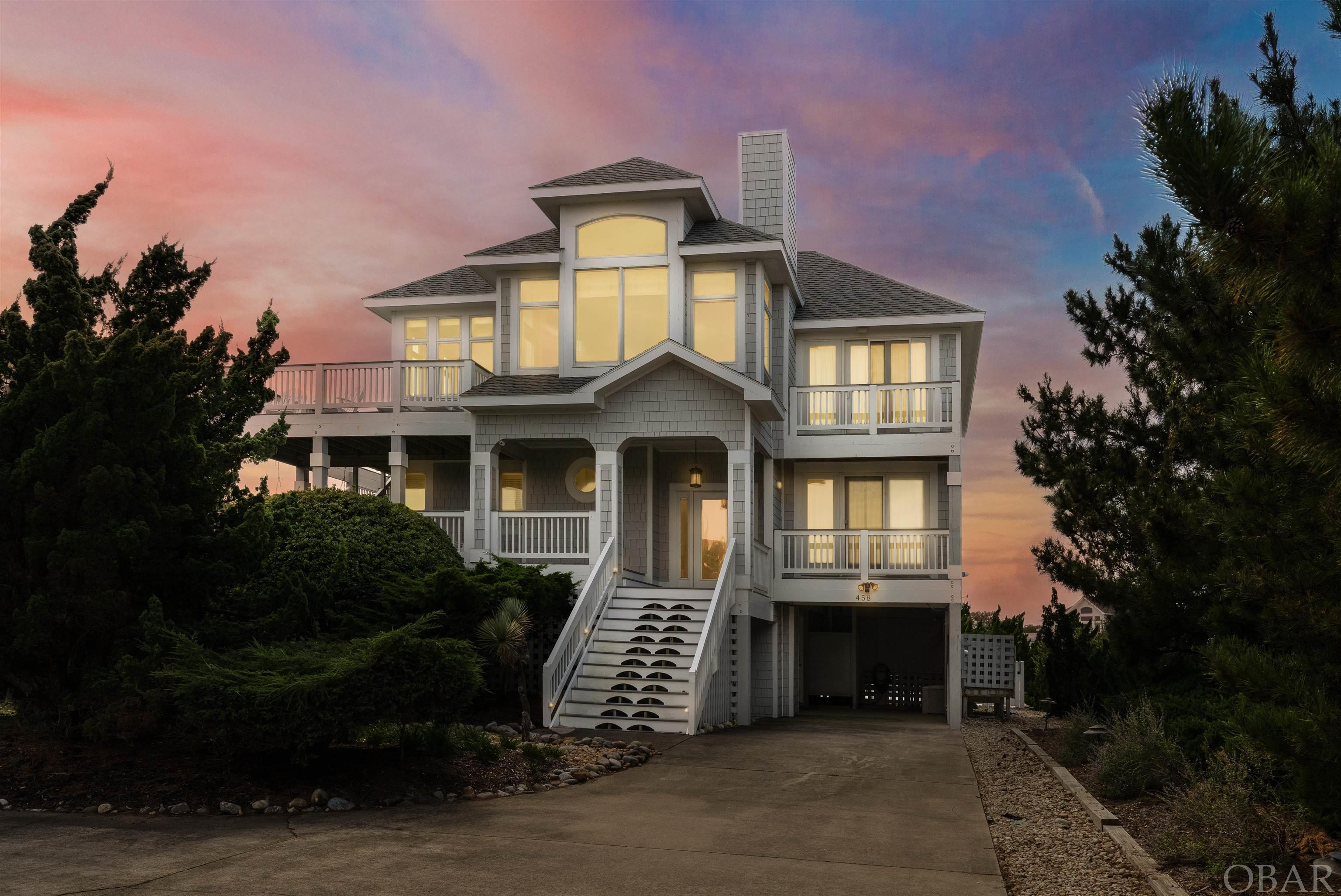 Custom built and impeccably well-maintained semi-oceanfront home situated on a quiet cul-de-sac in the sought after Pine Island community of Corolla. Boasting a well thought out floor plan, ocean views, ample home and community amenities, and a professionally appointed interior, this is one you don't want to miss! With major improvements made since purchase in 2000, and used as a second home since, this home shows like new. On the top floor a spacious open concept living room w/ gas fireplace, comprehensive audio & visual system with surround sound, ocean views, direct deck access, and a half bath serves as the perfect space to relax and unwind with friends & family. A gourmet kitchen boasting granite countertops, stainless steel appliances, a wine fridge, viking range, dual dishwashers and sinks, and both island & dining seating, is a chef's dream come true! Sneak away to the upstairs ships watch to play a game of cards or relax with a good book. Enjoy time soaking up the sunshine on the surrounding trex decks boasting ocean views and both dining and lounge seating. The top floor primary en suite offers a privacy deck, bathroom w/ custom tiled shower, plantation shutters, and a dual vanity, as well as a walk-in closet. A grand foyer entry welcomes you in on the second floor, leading to a sitting area to relax and unwind after time spent on the beach. This floor includes two en suites, and a spacious bedroom, all with direct deck access, as well as a full bath, and covered decks surrounding. Make your way down to the at home office with a writers desk and sofa, along with a privacy deck overlooking the private pool. The first floor boasts a game room with wet bar, surround sound system, and wraparound seating, a bedroom w/ walk in closet, and full bath. Enjoy the gorgeous private pool (built in 2021), an elevated and covered spa, outdoor shower, electric car charger, exterior storage space, and convenience to the beach access, and Pine Island community amenities within walking distance.