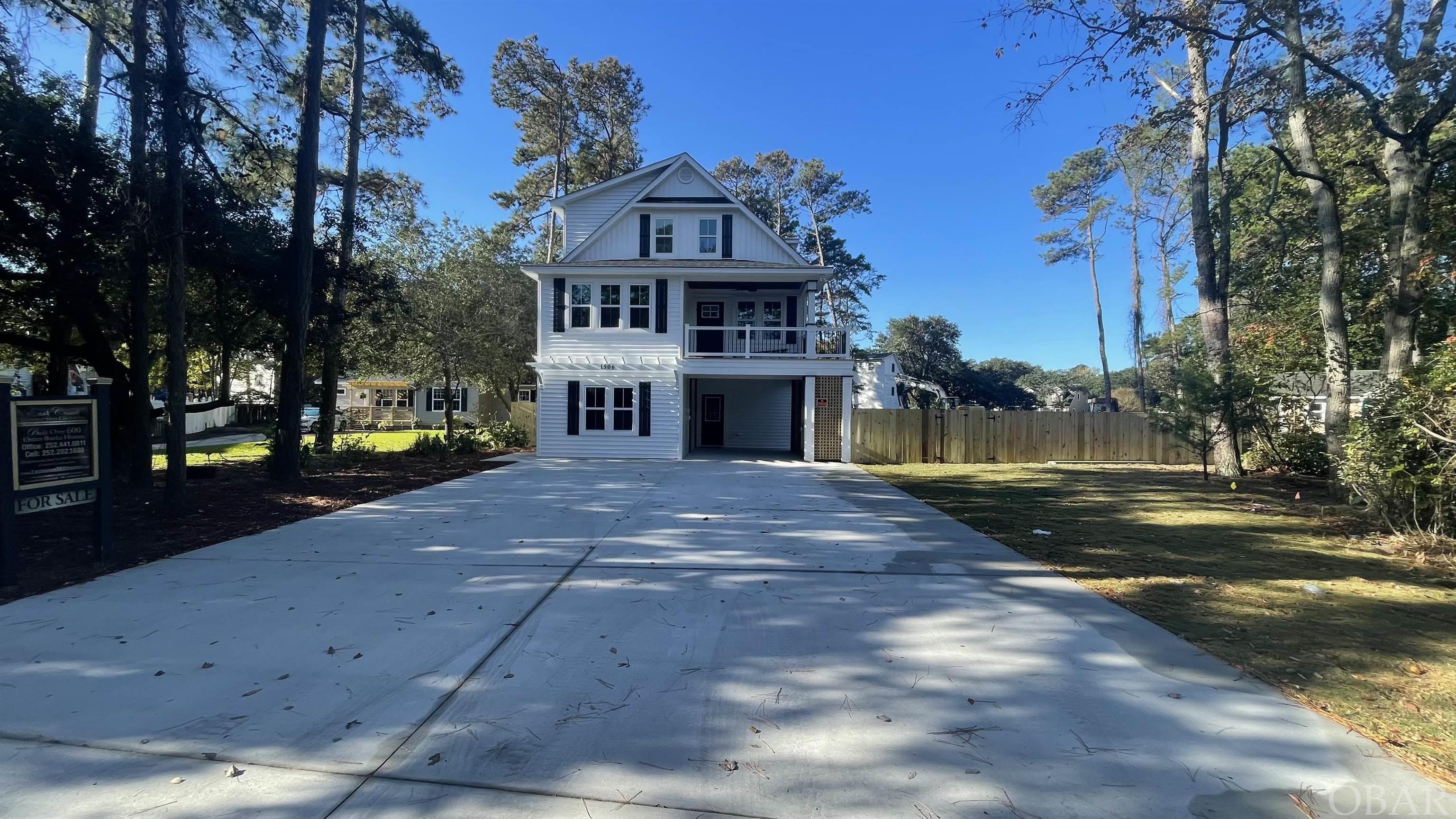 Complete by end of October. CUSTOM-BUILT 4 BR 3 and 1/2 bath NEW CONSTRUCTION in KILL DEVIL HILLS on RARE Lot approx. 15,000 sq ft (vs. 5000sq ft) COMPLETE WITH EXTENDED FAMILY SUITE/FLEX SPACE, KITCHENETTE, AND SEPARATE ENTRY on GROUND LEVEL! AND EXTRA BONUS ROOM TOP FLOOR! Ground-level-extended family/flex space features a kitchenette open living space with a farm sink, fridge, dishwasher, and microwave. The ground-level flex space also features a separate washer and dryer hookup behind the beautiful custom barn door. The ground-level ensuite has a large closet and built-in shelving. This home is perfect as a personal residence, second home, or investment, or live upstairs and rent the lower level to supplement your income! Tons of extras including privacy fence, sod, irrigation, and extended outdoor living space with built-in seating and TV hookup.  The entryway foyer, dining room, kitchen, great room, and hallways feature hardwood floors with hand-crafted trim. The open living space features a custom split face stone electric fireplace extending floor to ceiling, with customizable setting with changing colors! The kitchen features upgraded cabinets, quartz countertops, a farm sink, stainless steel appliances, and trendy lighting. The primary bedroom ensuite(mid-level) is accentuated with a tray ceiling and the bath has a quartz countertop, a custom marble shower, and a marble floor. The walk-in closet is ready for you with built-in wooden shelves. The laundry and half bath are hidden behind a barn-style door.  As you take the stairs to the upper level, notice the custom-crafted handrails and attention to detail. Each bedroom features upgraded polypropylene carpet. There are two bedrooms on the upper level with a shared bath. In addition, the top floor features a large bonus room. Imagine the possibilities such as an office, playroom or theater room!  The covered outdoor entertainment area features a custom bar, ceiling, and TV hook-up, expanding the home's living space. The outdoor area is large enough to include room for a future pool and pool house. (preliminary survey on file). As one of the most respected builders in the Outer Banks, Bill and Kim Lane have built over 700 homes, including luxury ocean speculative homes on the Outer Banks, putting the same care and quality into construction as they do the finishing details. The windows are all high-impact resistant, and the exterior walls are 2"x6" allowing for more strength and insulation. The home is a comfort-assured home with Lennox 3-zone 14 and 16 SEER system saving you money for years to come. This home is in a great location situated on a large lot with room for a pool, pool house, and extended outdoor living! Located in First Flight Village close to Multi Use Path, and nearby beach access on First Street. Enjoy being in the heart of KDH close to Publix,  theater, restaurants, Lowe's and the Wright Brother's Monument! X Flood Zone! Plans copyrighted. All pictures are similar to the new construction.