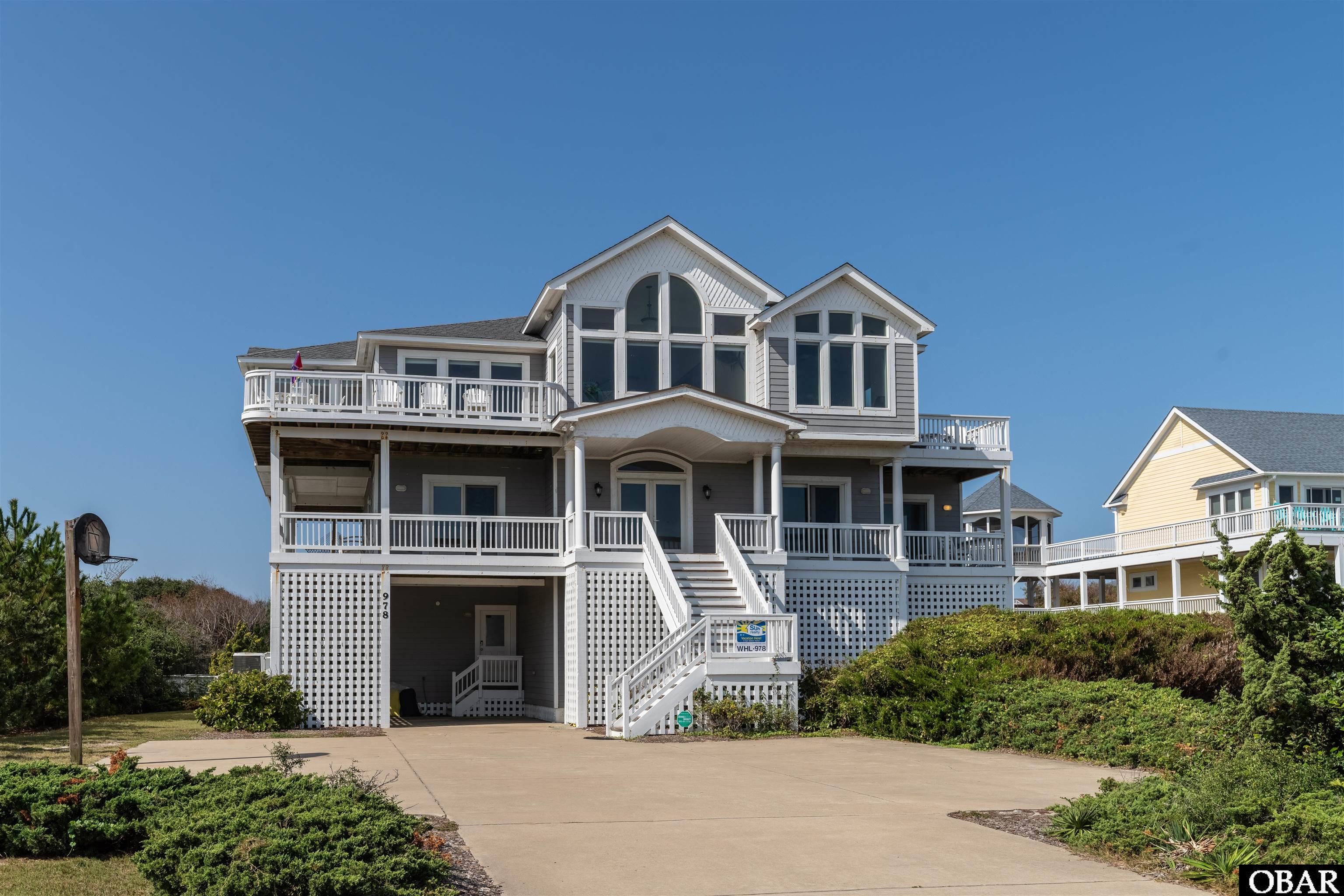 Stunning 10 bedroom estate situated on a spacious semi-oceanfront parcel, just steps to the beach in the heart of the Whalehead Community of Corolla. Boasting panoramic views of the ocean and a countless home amenity package, this is a home you don't want to miss! An open concept living room with large picture windows, a gas fireplace, wraparound sofa, and east facing decks serves as the perfect space to relax and take in the beautiful ocean view. A thoughtfully designed kitchen with stainless steel appliances and countertop seating, dual appliances, a wine fridge, as well as two dining areas, provide plenty of seating and room to prepare for family meals. Step out onto the top level sun deck to watch the sun rise over the Atlantic or to enjoy an afternoon cocktail at the high rise dining table. A half bath, king en suite with private bath, private balcony and fireplace, in addition to a king en suite with private bath (accessed from deck only) complete this top level of living. Relax and unwind after time spent soaking up the sun on the mid level which includes 4 king en suites with private baths (2 with deck access), a queen en suite with a private bath and deck access, an office/study, queen sleeper sofa, half bath, and covered decks. Make your way downstairs for more entertainment where you'll find the rec room with pool table, card table, and a kitchenette with full sized refrigerator, microwave, and dishwasher, in addition to a theater room, arcade area perfect for kids, queen en suite with private bath, two pyramid bunk bedrooms with trundle beds, a full shared bath, and half bath. Step outside to the private pool area with hot tub, half bath, covered cabana bar, outdoor shower, and spacious fenced and landscaped backyard. Enjoy the convenience of a full-sized laundry room with storage, an elevator to all levels, community beach access just 350 feet away, and local shops & dining within walking or biking distance! It's no surprise that this is a sought after home to vacation with friends, family, and guests alike each year!