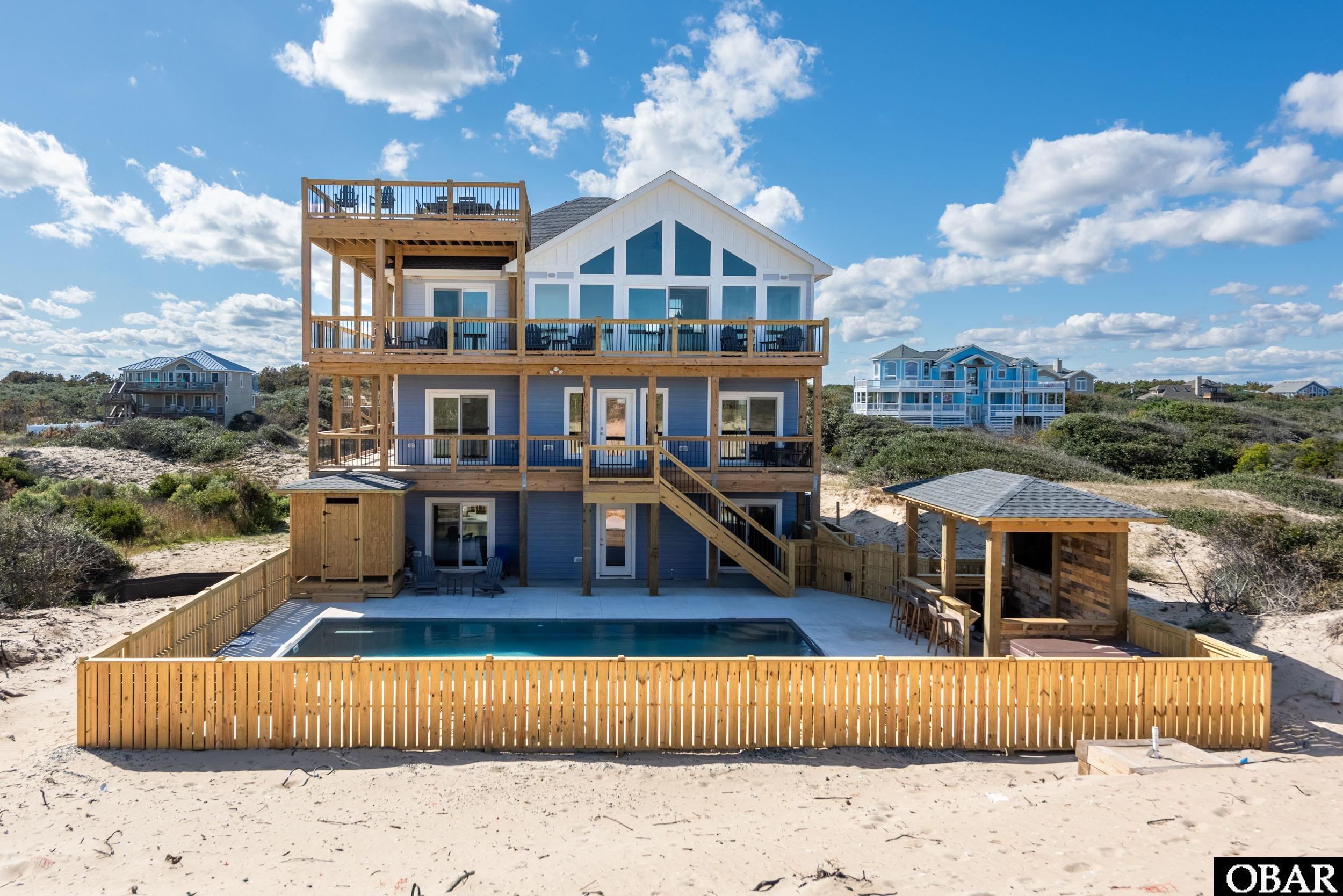 Stunning Oceanfront Home completed in September of this year, making this nearly New, saving you the time of building. This house is turnkey with Amazing Outdoor spaces on all levels. High End, Well Stocked, Gourmet Kitchen for the Master Chef, with Wet bars on all 3 floors. The Dining Room has live edge Dining tables and seating for 30, not including the bar. State of the Art Sono's Sound system indoor and outdoor with I-pads to control the zones from any level. Wifi Extenders help send the signal to all corners of the house for ease of use. Office Nook with Ocean Views tucked off the top floor Great Room for those who need to check emails or work while at the Beach. From design through construction along with furnishing, the house shows the finer side of things. Catch the sunrise and sunset while watching the waves roll in on the 3 sided Rooftop deck with Panoramic Views. A must see.  Enjoy the simple luxury in one of the 10 Master Suites. Outdoor Poolside is built for FUN. You can watch the game in the cabana while in the pool or relax in the hot tub with music streaming from the outdoor speakers. Light the firepit for the ultimate poolside experience while under the Carolina Stars, and it surely will be a memory of a lifetime. On a rainy day, enjoy a movie in the Theatre with seating for 13 and a Pelaton Bike for the fitness minded folks. Relax in the Pub with Poker table, PUB tables, wet bar with beverage center and icemaker, multiple TVs, Sono's music. Many upgrades including 2 Built in Bunk Rooms, Spray foam insulation, Trex decking in Crows Nest, and Aluminum Balusters, make for a truly stunning and efficient house.  Book your appointment today, it wont last long.