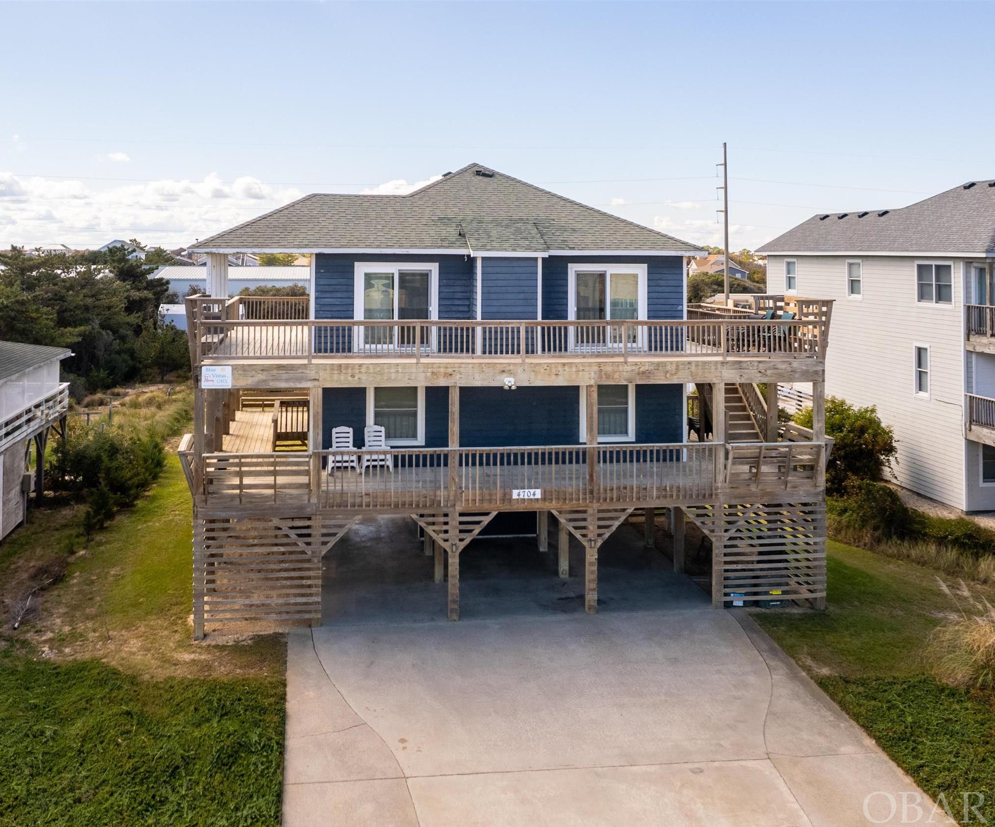 With it's stunning and expansive ocean views, large porches, oversized lot, proximity to beach access, and great rental numbers Blue Vistas exemplifies Nags Head charm!  The designated open space across the beach road provides an unobstructed view of the Atlantic Ocean. The upstairs great room is spacious with a white tongue and groove ceiling vaulted ceiling, which gives a modern feel to the traditional Nags Head beach home. In 2017 new flooring was added.  The exterior was painted in 2016 and all new hurricane windows and slider doors were added (minus two sliders on the south side of the home).  The home is set as a 4 bedroom, but the septic is rated for a 5-bedroom, offering the option for future potential expansion. At 13,000 sq/ft the lot is larger than most normal semi-oceanfront homes, with room to add a pool.  The large driveway can accommodate more than 6 cars and allows for turning around, so that departure is headfirst on to beach road.  Centrally located between Jockey's Ridge State Park and Nags Head Golf Links, and some of the best OBX restaurants and shops, all while having two public beach accesses within 1/4 mile. Proven rental history with room to grow! Schedule your appointment to see this home today.