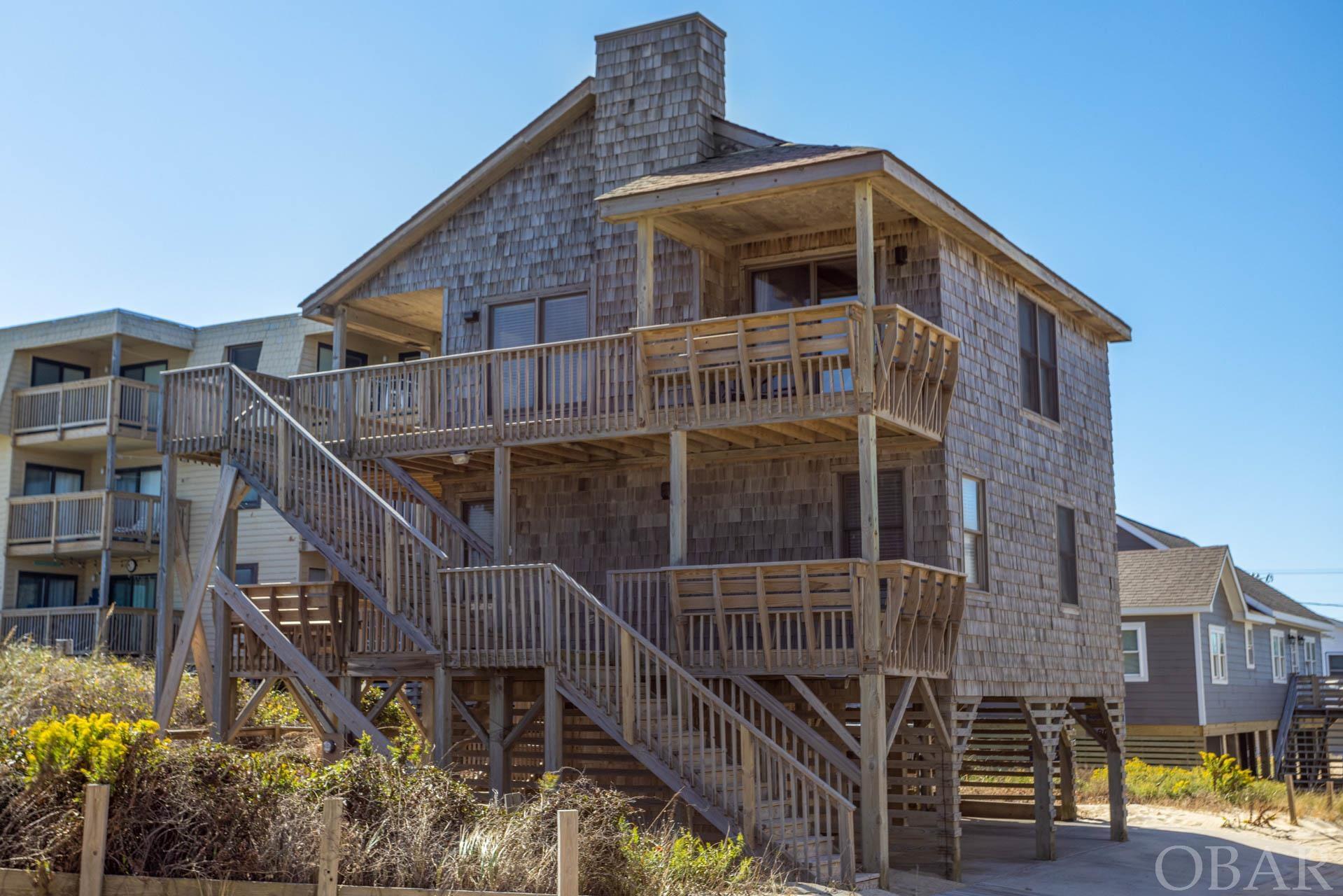 Nestled just 50 ft from the sand, this Kill Devil Hills semi-ocean front home is an ideal sanctuary for those who seek the perfect blend of comfort, convenience, and captivating views. The double layer decks offer the perfect vantage point to soak in the soothing sound of the waves and relish in the stunning Outer Banks sunrises and sunsets. Inside you'll find 4 good-sized bedrooms and 2 1/2 baths with a reverse floor plan. Hardwood flooring runs throughout the home with tile in the bathrooms. The top level is an open concept with full ocean views from nearly every seat. The electric fireplace is the perfect spot to quickly warm up on cool evenings. The kitchen and bathrooms have been updated and the decks replaced in 2022. Beyond the beach, you will find an array of dining options, ensuring you'll never venture far for a great meal. This property is your ticket to the ultimate beachfront lifestyle. Don't miss your chance to own this stunning piece of paradise.