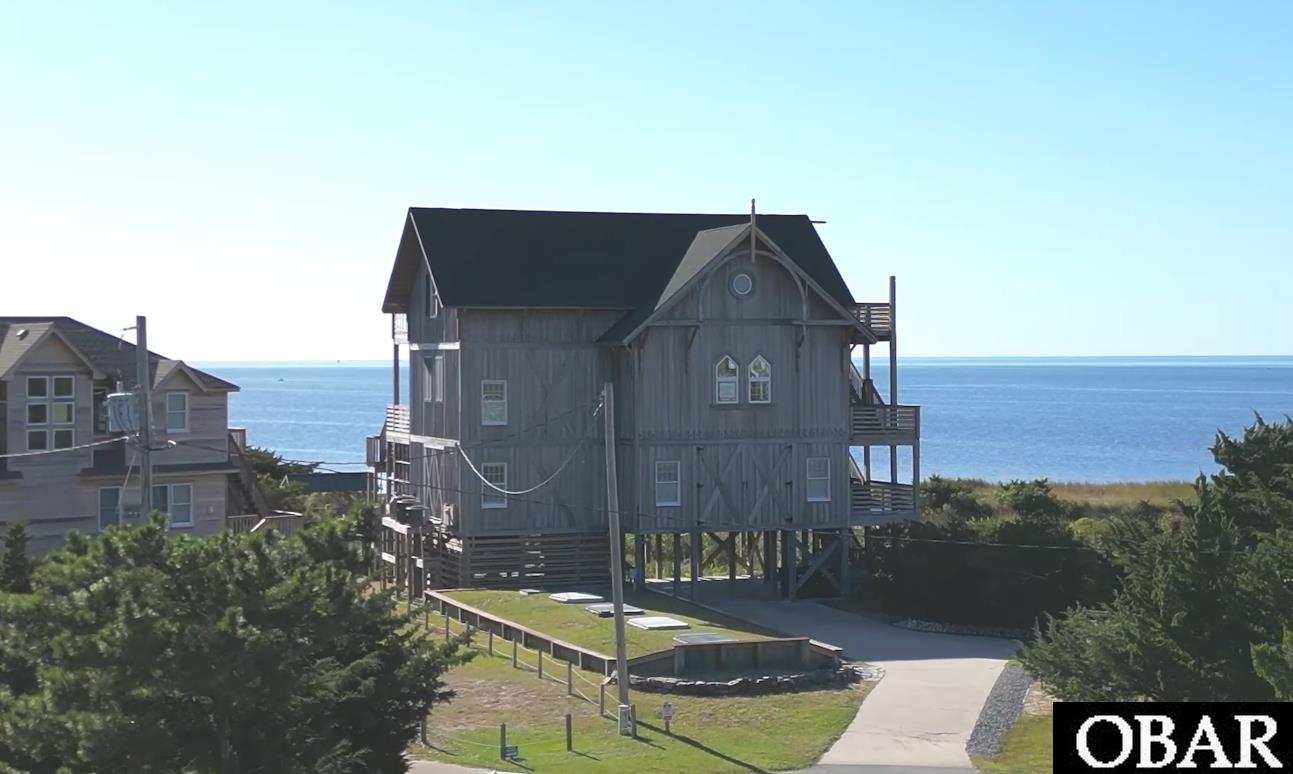 For the first time ever, this iconic Avon soundfront property is available for sale!  Modeled after historic lifesaving stations along the Outer Banks, this home is truly one of a kind - there's not another one like it!  And the location is just as unique as the house itself - with its own stretch of soundfront beach, a salt marsh where you can watch birds and wildlife play in the sun, and world-class watersports access literally in your backyard.  Enjoy wide panoramic sunsets on the covered lower level decks or walk out onto the top deck to work on your suntan as you look out over the Pamlico Sound.  Access the secluded beach down a romantic path - imagine your children and grandchildren having weddings along the water while the friends and family look out from the decks of this amazing property.  Situated just a few hundred yards north of "Canadian Hole," the shallow waters and steady winds behind this home are prime real estate for windsurfing, kiteboarding and stand-up paddleboarding.  Step inside the ground-floor elevator and take a ride through 3 levels of coastal living.  On the first floor you'll find a wet bar and game room.  There's an ensuite bedroom/bathroom, another bathroom and a flex room.  On the second floor you'll find the open living area with tall ceilings, beautiful engineered hardwood floors, and an open kitchen with beautiful quartz countertops.  Also on this level you will find another ensuite bedroom/bathroom, and if you walk out the tall sliding doors that frame your Pamlico Sound sunsets you'll find the hot tub on the deck.  On the top floor there's a large sitting area with a fireplace, and two more ensuite bedroom/bathrooms.  With right at 4,000 sq ft of living space this home can host large parties but you might want to spend your time outside instead!  There's a soundfront private pool with a tiki bar, TWO outdoor showers and two underrated perks of this Avon location - you're a short walk down Park Dr to public beach access on the south end of Avon, and there's plenty of parking for large family gatherings or hosting guests.  The back of this home is lined with windows and sliding doors to capture every sunset and the panoramic views of the wide open water will take your breath away.  Spend evenings on your deck watching the light of the Cape Hatteras Lighthouse.  Pictures won't do this property justice, if you have dreamed of owning a showcase home on Hatteras Island then check out Dolfins Folly today!