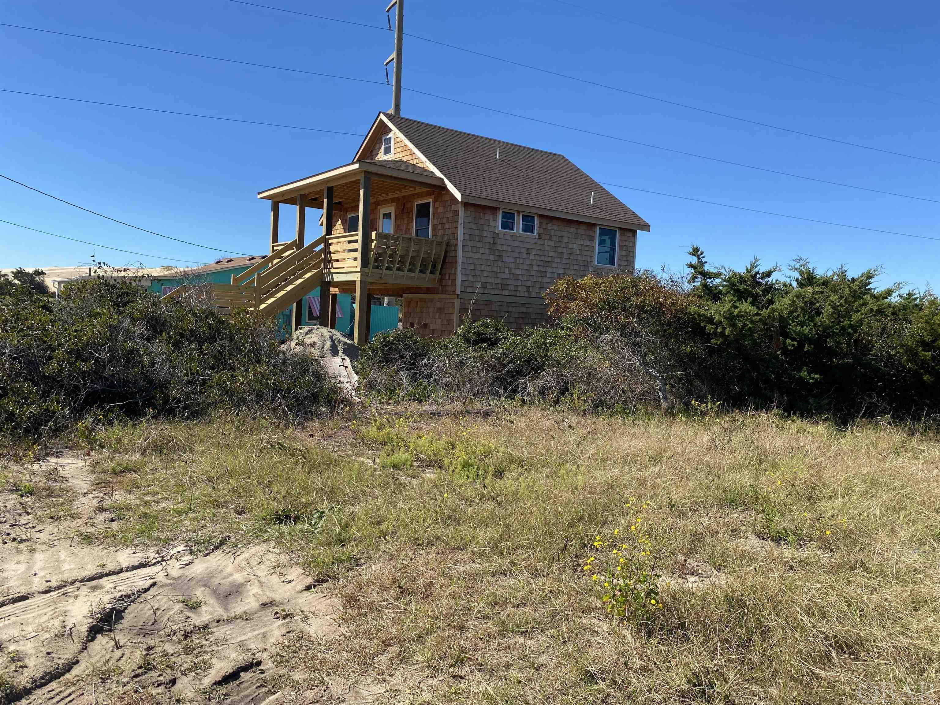 A classic Old Nags Head house that has been totally remodeled. This tiny 3 bedroom 2 bath house was gutted, raised on pilings and totally redone.  New wiring, plumbing, insulation, roof, AC, windows, decking, railings, stairs pine flooring, bathroom fixtures and appliances. Many of the interior walls will be painted wood If you are looking for a small house with the Old Nags Head vibe this one is for you. Sit on the built in front porch benches and enjoy ocean views to the east or watch the kites and hang gliders soaring over Jockeys Ridge to the West. Store all your beach toys and bikes in the large utility room. House is under construction please be careful.
