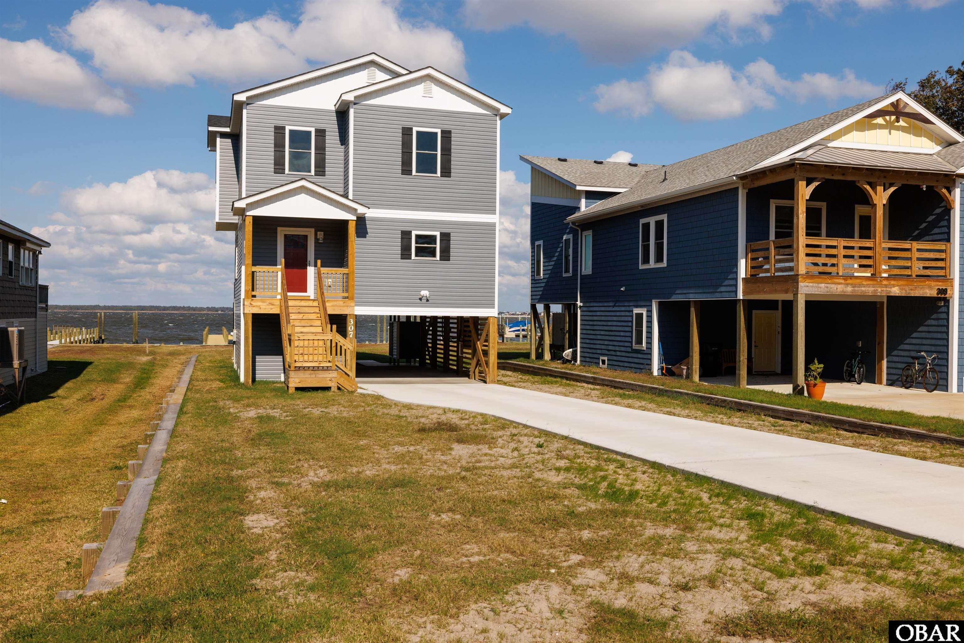 New Construction! Beautiful soundfront home with pier and boat dock. Tranquility at its finest.  This home has spectacular views of Kitty Hawk Bay, Albemarle Sound and Currituck Sound. There is nothing like these magnificent vistas of water and sky to soothe your soul. Both levels of this wonderful home have desirable nine foot ceilings with ceiling fans and they exude a sense of openness. The great room is spacious with beautiful wood floors and has a sliding glass door that opens onto a large sun deck.  A legion of windows reveal the panorama and, with the addition of transom windows, expand the sky views.  The kitchen has granite countertops, all stainless steel appliances and an island for extra counter space, perfect for entertaining.  There is also a convenient half bath just off the great room and an enclosed space with a new washer and new dryer. The three bedrooms are located upstairs and carpeted and also have 9 ft. ceilings with ceiling fans. The capacious ensuite master has breathtaking water views, tiled bathroom floor, granite two-sink vanity, a beautiful walk-in shower and a soaker tub. The two guest bedrooms share a nice bathroom with tile floor and a granite top vanity. The exterior of this gorgeous home is vinyl for easy maintenance and an there is, of course, an outside shower--a must for a waterfront home.  A ground level entrance through a large utility room provides a dry entry and tons of storage space. The brand new 98 ft. pier with boat dock completes this dream package. Fish off your own private pier and dock your boat to keep it ready to go! The home is brand new and being sold with a one year general builders' warranty. Colington Harbour is one of the most sought-after neighborhoods on the Outer Banks. There is a convenient boat ramp at the community marina that provides easy launching and quick access to Albemarle Sound, Kitty Hawk Bay, Currituck Sound, Roanoke Sound, Croatan Sound, Pamlico Sound and Oregon Inlet for entry into the Atlantic Ocean. Incredible fishing, sailing, power boating, jet skiing, kayaking, windsurfing and kitesurfing! There is also a nice soundside park for picnics and great area for children to play. Join the club for $250/year and have access to the large community swimming pool and tennis court. Colington Harbour is a fantastic gated community. You won't find a better neighborhood for comfortable living and fun.