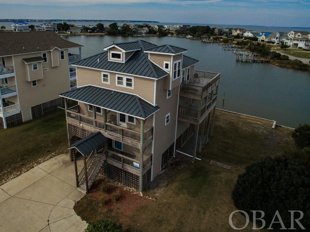Welcome to your dream coastal retreat! This extraordinary 4-bedroom, 4.5-bathroom offers a slice of paradise in the beautiful Nags Head area. Step inside this impeccable, well-maintained home and be captivated by the exquisite details and stunning features that await. The open floor plan seamlessly combines the spacious living areas, creating a warm and inviting atmospheres for all. The vaulted ceilings and ample windows allow an abundance of natural light while you take in the 360-degree views of the harbor and the sound. The kitchen is well-appointed with stainless appliances, a convenient pantry, and durable quartz countertops. The bedrooms in this home are truly special as each one boasts its own private bathroom, ensuring comfort and privacy for everyone. Wake up to breathtaking views from every window and savor your morning coffee on one of the many sun decks or covered decks. For those seeking outdoor adventures, this property is a boater's delight! With a boat dock right at your back door, you can easily explore the nearby popular fishing spots near Oregon Inlet and Wanchese. After a day on the water, rinse off in the refreshing outdoor shower before relaxing in the ships watch area with its awe-inspiring panoramic views. You won't find a better sunset to unwind to on the Outer Banks! Conveniently located close to all that Nags Head has to offer, this home provides easy access to beaches, dining options, numerous water sports, and more. Don't miss out on this incredible opportunity to own a piece of coastal paradise!