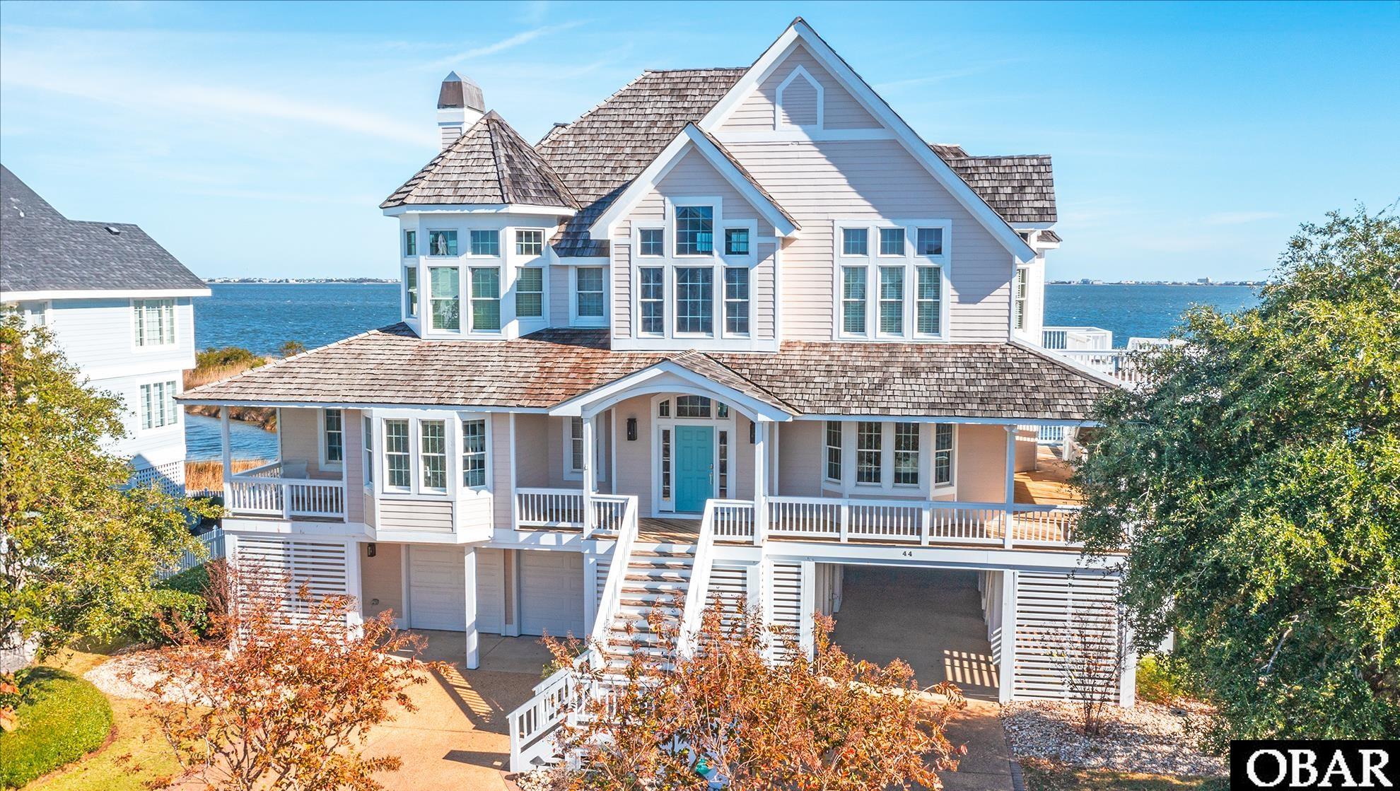 Welcome to 44 Ballast Point Drive - A stunning waterfront home in Ballast Point-Pirates Cove that boasts unrivaled quality and attention to detail. The home is perfectly designed to take full advantage of the Soundfront water views, making it a true gem for anyone looking for an exquisite living experience.   One of the most impressive features of this home is the top level soaring cathedral ceilings that create a grand atmosphere. The 20' curved granite bar is the centerpiece of the home with the focal point of the waterfront views and is perfect for entertaining guests in style. It comes fully equipped with an ice maker, undercounter refrigerator, custom cabinetry, and pull-out shelves with more than enough space for a full bar setup.   The top floor of this home includes an expansive living area with beautiful hardwood flooring, a gas fireplace, built-in entertainment cabinetry center, a den/office or extra sleep area with a barn door enclosure, dining room and gourmet kitchen.  The spacious kitchen is a chef's dream, featuring a 4 grill gas burner stove, double wall ovens, built-in microwave, a sub-zero refrigerator, Bosch dishwasher, wine cooler, corian countertops, a huge pantry with custom shelving, under counter wine cooler.  This top floor level also has a full bath.   The home boasts a 9' Andersen French door that allows you to take in the breathtaking views of the surrounding water. The mid-level comprises of the primary suite with its own private fireplace, cedar walk-in closet, whirlpool tub, and tiled shower, an additional guest suite and two guest bedrooms, all with French door access to outside decks overlooking the water. New carpet in 2021 in the bedrooms and Hand Crafted Hardwood, Mannington "Sanctuary Fresh Air" flooring on the top level, main stairs, foyer and lower level steps and entry.  Additionally, an ELEVATOR from the bottom level is provided for easy access to upper levels. Additional features include a Tankless Gas Hot Water Heater and  Roof is original 50 year Cedar Shake Roof Shingles . The home has a vast, 22X22 (2)-car garage, plus additional underneath parking, storage and workshop/tackle room with a mini split heat and ac unit, an outside shower, and fish cleaning table with water faucet.  This home is an avid fisherman or boater's dream with 100 feet of water frontage, bulkheaded with a private beach and community sandy beach right out back.  Lighted private dock with bench seating, and a manicured lawn with an irrigation system.  Slip #20 in Ballast Point Canal is assigned to 44 Ballast Point with an annual fee of $130/yr.  The home is also ideal for a primary, second home or vacation investment property.  Pirates Cove is a 24/hr gated community with roaming security. Onsite Restaurant, Tiki Bar with summer music entertainment. A Ships Store for essentials and a full service marina with fuel docks.  Amenities include a Clubhouse for social events, pool with snack bar and game room.  Lighted tennis courts, play ground, volley ball court, community pavilion, fitness center and miles of lighted docks to walk or jog on.    Overall, this waterfront home is the perfect blend of luxury, comfort, and style. Don't miss out on the opportunity to make it your own. Contact us today to schedule a viewing. Please see associated documents for exclusion list upgrades and unique features.