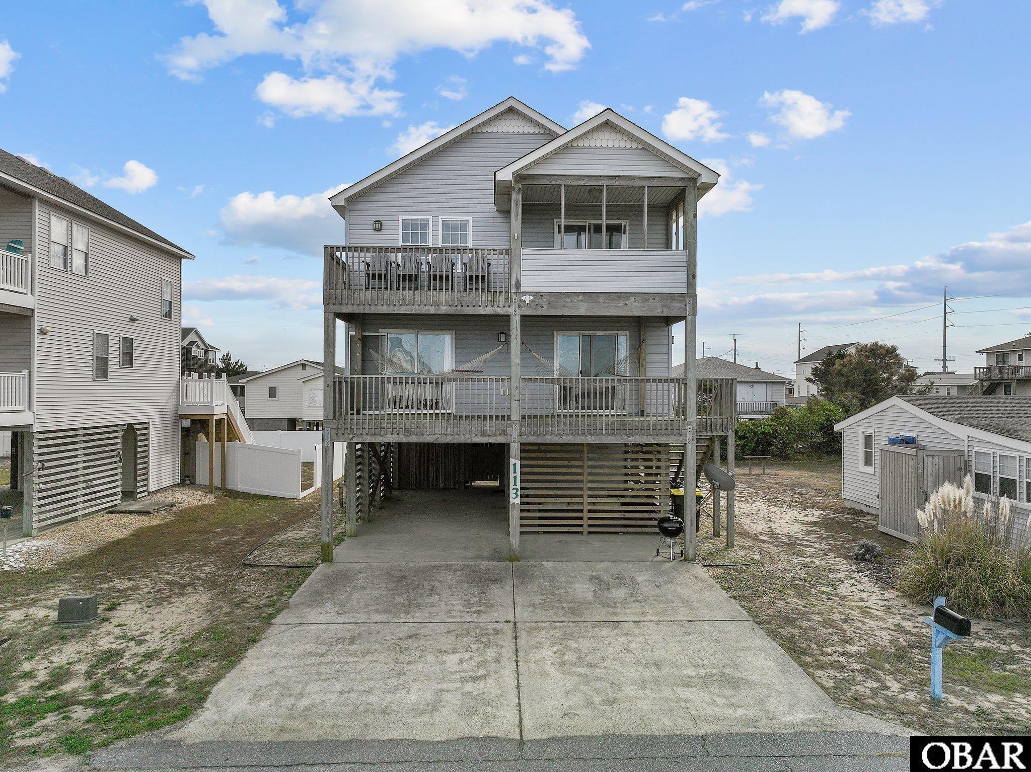 Your Outer Banks Oasis- Enjoy the classic beauty of the Avalon Beach area while relaxing in modern style. This 4 bedroom 3 bathroom home has plenty of amenities to create a serene beach getaway. Centrally located, the property is close to Avalon Pier, Awful Arthur’s Oyster Bar, Target, and various grocery stores and restaurants. The public beach accessed at Avalon Pier or Fifth Street are just a short walk away, so no need to fight for parking.   The reverse floor plan provides beautiful natural light all day long. A spacious living area with high ceilings, brand new appliances, and a table to fit the whole group is highlighted by a custom driftwood light fixture. The open living area leads to an outdoor covered top level dining area. The top level deck is the perfect place for a sunrise cup of coffee or a sunset happy hour. This top level also has a cozy queen room with an attached full bath with two sinks.  The mid level has three large bedrooms. The south facing room has full over queen bunk beds and enough floor space for an air mattress. The two north facing rooms have direct access to the mid level deck. These rooms both fit king beds comfortably and one is an ensuite with a full bath attached. There is also a full bath in the hall. Lots of room to relax on the mid level deck and swing in the two Nags Head Hammocks enjoying the cool ocean breezes. The mid level is home to the washer and dryer and an additional lockable owners’ closet containing the water heater. Out back, you will find a spacious south facing deck that is pre-wired to hook up a hot tub.   The large carport offers a dry entry, plenty of space for multiple vehicles, and a large outdoor entertainment area. The covered area with bar seating and two couches is the perfect place to hang out while dinner is on the grill or enjoy some relaxing time in the shade in the afternoon. A large beach closet is perfect for storing all your sandy gear. It is lockable so guests can have peace of mind their belongings are secure. There is also a large outdoor shower with a hose hookup perfect for rinsing sandy toes. The entryway features an additional owners’ closet that is able to be locked.    A brand new roof and brand new appliances were installed in November. The rear deck that is wired for a hot tub was resurfaced in December. AirBnb listing information, additional photos, and reviews can be found here:  https://www.airbnb.com/rooms/37778377