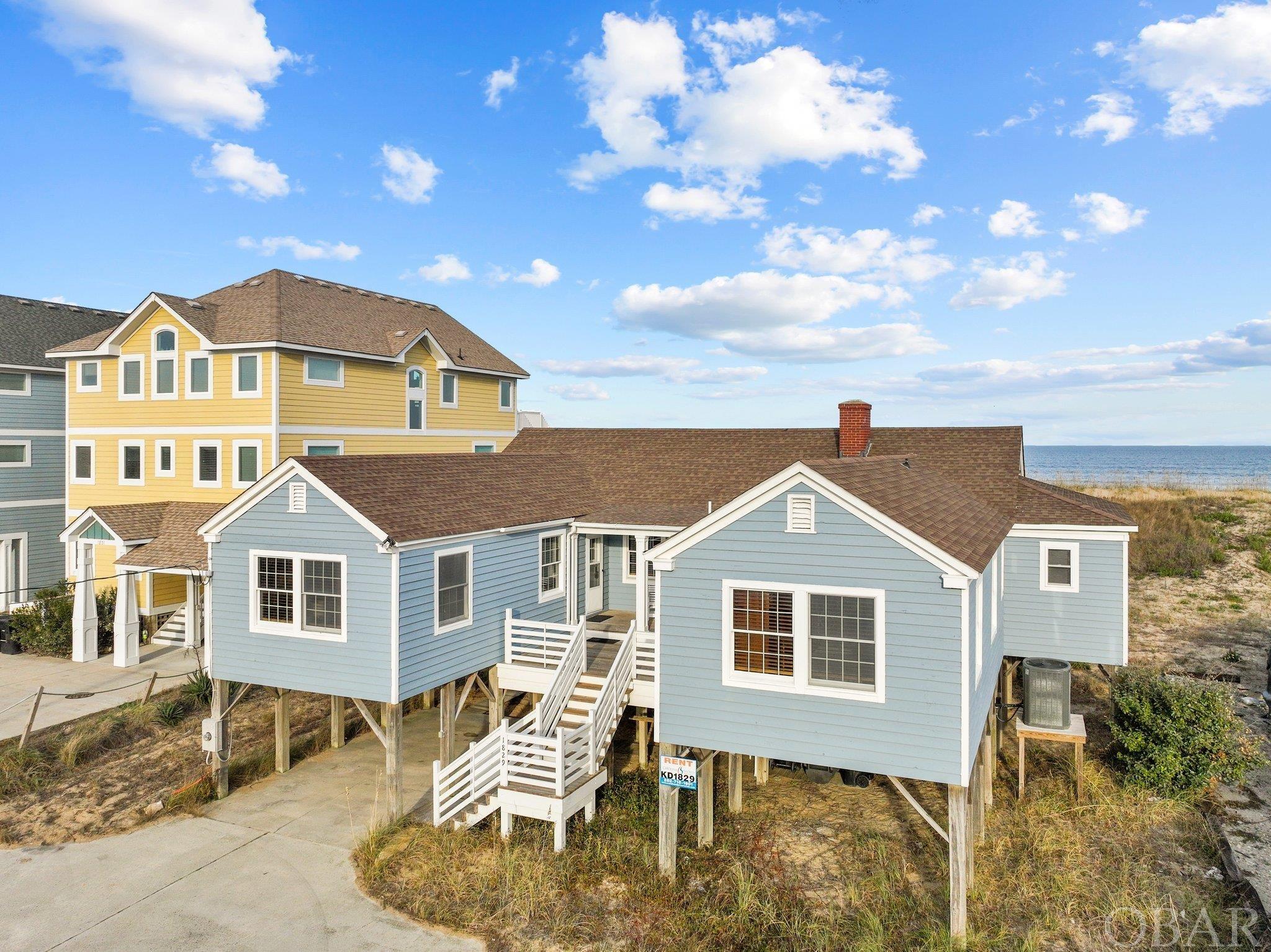 Classic Oceanfront Cottage on a rare 75ft Wide Lot.  Ocean Views!  Huge 19,000 square foot lot with a wide and vegetated dune!  Step into a piece of history on the shores of the Atlantic Ocean with this vintage gem nestled in the heart of Kill Devil Hills, NC.  This 4-bedroom, 3.5-bathroom home stands proud on an expansive 75ft wide oceanfront lot, a rarity that sets it apart.  Witness breathtaking panoramic views of the Atlantic from your doorstep, complemented by a wide sandy beach and a protective dune—a unique blend of beauty and safety.  The property's depth and elevation provide an assurance of tranquility and security.  Built in 1945, this classic Outer Banks cottage exudes timeless charm, boasting hardwood floors and solid T&G wood walls that whisper stories of a bygone era.  Merging the nostalgia of yesteryears with modern comfort, the property features a new roof, freshly painted exterior, new decks perfect for lounging, and a brand-new private boardwalk leading directly to the ocean.  Enjoy the convenience of a central location in Kill Devil Hills, where entertainment, dining, and shopping options abound, catering to both residents and vacationers alike.  There are so many possibilities to use and enhance this amazing oceanfront property.  It is charming and comfortable and can be enjoyed immediately.  Due to the size of the lot, expansion and the addition of a pool may be an option.  Additionally, this would be an amazing property to start fresh and build your new dream home. This is a one of a kind home and a one of a kind opportunity.  Don't wait!