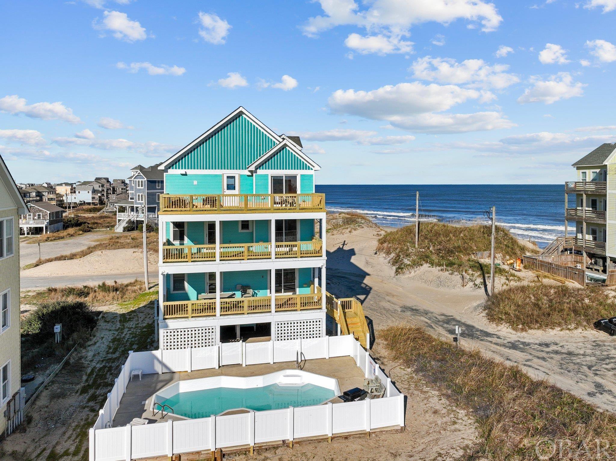 Experience coastal living at its finest in this Oceanside home in Rodanthe on Hatteras Island. Just one lot away from the oceanfront, enjoy easy beach access and a quick walk to Rodanthe Pier. Revel in breathtaking views from every level, spanning from the ocean to the sound. The renters love this home as it generates great income year after year; sleeps 17 and has a nice bunk room that adds extra space along with 5 ensuite bedrooms and fantastic amenities. Relax in the spacious great room with cathedral ceiling and open kitchen and dining for 16. You won't miss the custom tile compass rose on kitchen floor and double dishwashers for your larger groups. Each bedroom has it's own private bathroom with beautiful tile upgrades. There is a flex room that is currently used as a bunkbed room featuring double doors leading out to the game room with pool table and a wetbar with 2 mini/beverage refrigerators. Gorgeous hardwood floors throughout common areas and nice 6-panel wood doors are a step up to quality construction. This beautifully furnished vacation rental with all the amenities generated an impressive $125,000 in income last year.  The home is handicap-friendly, featuring an accessible bedroom and bathroom with the convenience of an ELEVATOR servicing all floors. Unwind by the private pool with ocean vistas, and indulge in year-round relaxation with the brand-new hot tub. Your coastal retreat awaits!  Recent 2023-24 upgrades include newly replaced decks and railings on rear and top levels, brand new hot tub and hot tub deck, new pool fence, new couches & chairs in living room and crows nest and fresh interior paint. Other recent items replaced are kitchen appliances(2020-2022), refinished hardwood floors(2021) and one HVAC(2021).