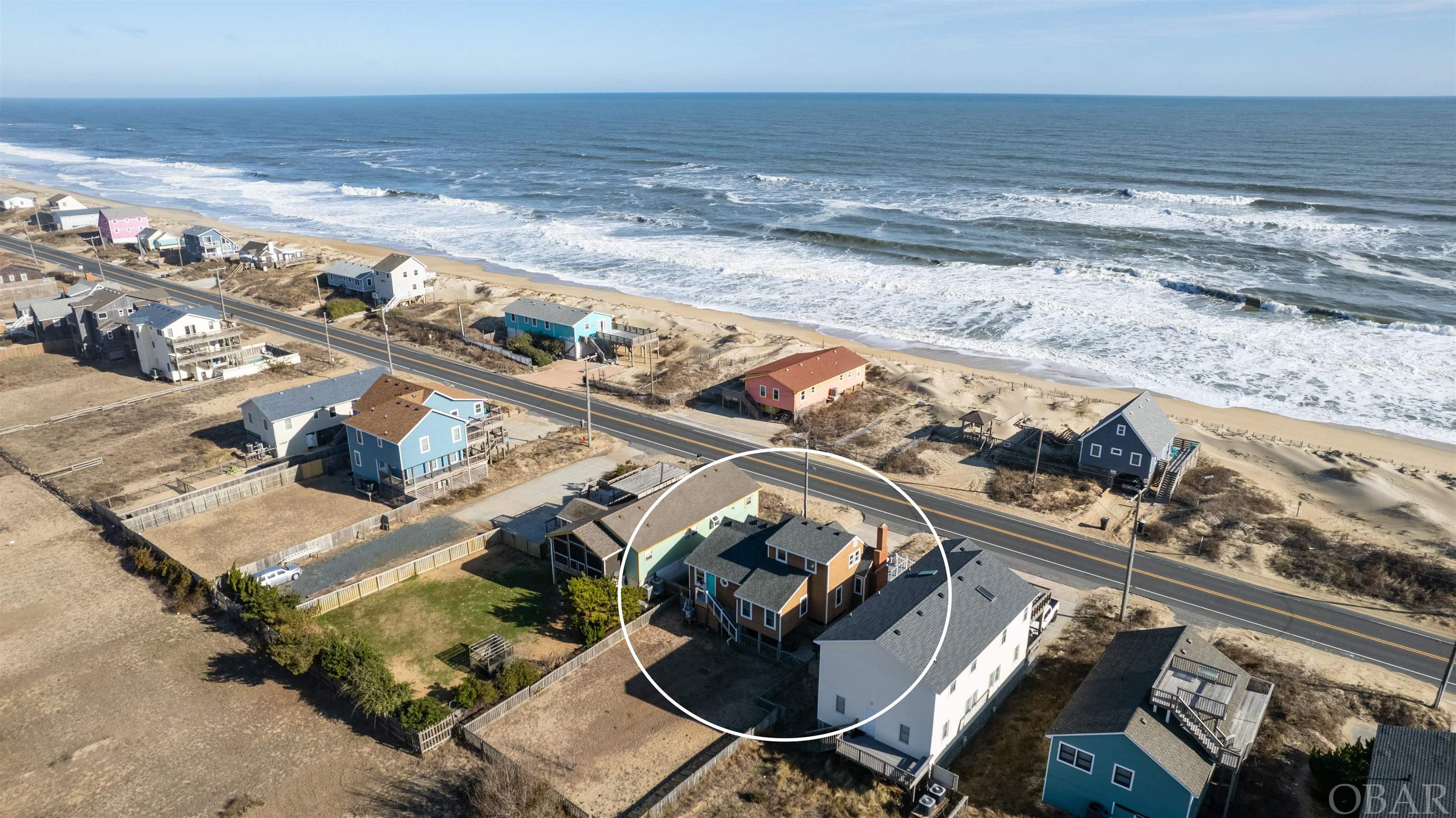 Enjoy Oceanfront views that will never change and great beach access without the risk of being right on the Oceanfront! 'The View Cottage' is truly one of a kind and has been renovated over the years, keeping its charm and character while adding modern conveniences.  The effective age is much newer than 1950, and it sleeps like a 4 bedroom (sleeps 10!).  The large ocean view window and sliders in the living area fill the space with tons of natural light, and you will love all the details throughout like the bead board ceilings, original doors, and gas fireplace with tongue and groove wood work.  The kitchen was remodeled by Ken Green and showcases Geos recycled glass counters, a wet bar with wine cooler, glass front cabinet doors, and a custom pull out pantry.  The main level also features a Queen primary bedroom with en-suite bath, a double bunk room, a full hallway bathroom, custom built ins, a 500 game arcade, and a laundry area.  Relax on the brand new oversized front deck with new hot tub where you will experience beautiful ocean views, sunrises, and gorgeous moon lit nights over the ocean. You will be so close to the ocean that you may see dolphin right from the front deck on any given day!  The 2nd level offers 2 additional bedrooms (Queen and Full) that share a hallway half bath.  You will find plenty of storage with lots of closet space throughout, and a pull down attic with flooring and Thermax insulation.  The front Ocean view sun deck offers plenty of seating with quality polywood furniture, and the exterior carport area provides a great shaded additional outdoor living space with a sofa, table and chairs, picnic table, and outdoor shower.  Hurricane shutters on the front windows and doors offer added built-in protection when needed. The fenced in backyard is perfect for lawn games, and you will find everything you need in the utility shed from corn hole boards to beach gear and a beach cart to carry everything over to the beach!  You will fall in love with this adorable cottage that offers all the comforts of home and an absolutely ideal location in Kitty Hawk.  You will never lose your Ocean views as the vacant Oceanfront lots are not buildable.  Over 10% estimated gross rental return with up to $106K projected for the 2024 season!  Recent upgrades include a NEW exterior electrical service panel and new water heater '22, NEW smart tv's, and a brand NEW front and back deck with trex, NEW deck pilings, NEW hot tub, NEW fortified roof, and NEW main level heat pump in '23. The views are even better in person, and you cannot beat this location in Kitty Hawk!