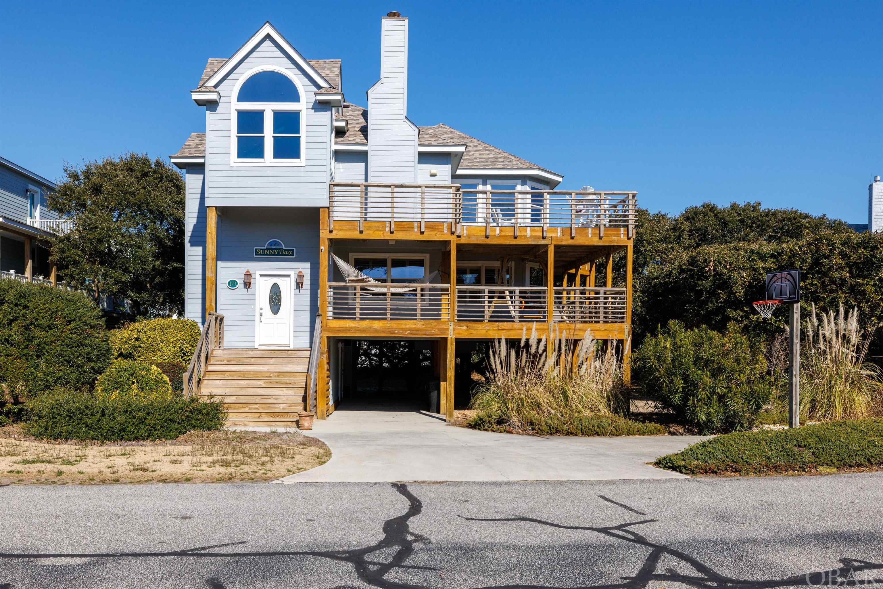 With sparkling ocean views inside and out, resort-style neighborhood amenities, and easy access to idyllic downtown Duck shops and restaurants, this wonderful 4 BR | 3.5 BA home in Schooner Ridge is what OBX dreams are made of!  As you enter you'll be greeted by a gracious front foyer with beachy colors and a tiled entry.  Head upstairs to the top floor kitchen, living and dining area where gorgeous ocean views await!  The freshly-painted kitchen is crisp and clean, with quartz countertops, large pantry, and a breakfast bar perfect for serving up appetizers or grabbing a quick snack.  The kitchen flows seamlessly to the dining room, surrounded by windows for beautiful views from every seat at the table.  The living area provides a spacious yet cozy hangout, with an electric fireplace insert for added ambiance on winter evenings, or head up to the ships watch (complete with wet bar) for a lively game night.  Step outside to watch the sunrise over the ocean on your massive sun deck or enjoy a golden hour cocktail in the shade of your covered deck space. The top level also features a large powder room as well as a well-appointed primary suite and private bath with double vanity.  On the mid-level, you'll find a cozy lounge perfect for watching a late-night movie, along with two nicely-appointed bedrooms sharing a large hall bath with double vanity.  A second primary suite completes the mid level with private ensuite bath.  The laundry room is also conveniently located on this level, along with expansive covered porches and a soothing hot tub.  Catch the afternoon ocean breeze as you swing or relax in your hammock.  The ground level offers a tiled dry entry and abundant storage, inside and out, as well as a double outdoor shower.  Located in amenity-rich and highly sought after Schooner Ridge, offering a community beach access, oceanfront outdoor pool, indoor pool, tennis and racquetball courts, fitness center, gameroom, and playground, you’ll have all the luxuries of resort-style living right outside your door.  Come see what makes this home - and neighborhood - so special...book your tour today!