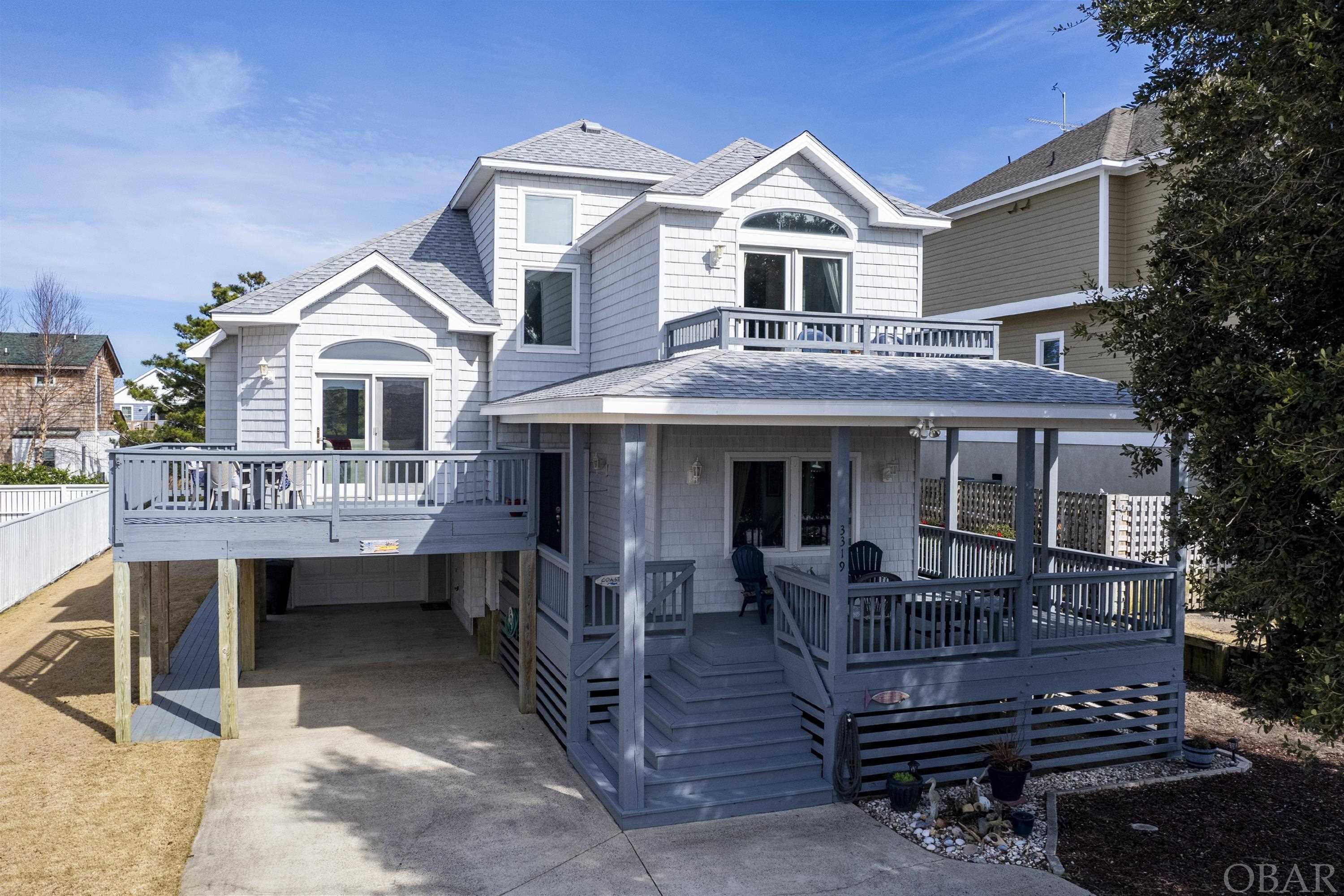 OPEN HOUSE SUNDAY 4/28, 1-3pm!!Beautiful two-story home situated on Bay Drive, awaiting picturesque sunsets!  Views of lovely Kitty Hawk Bay from across-the-street sound front are just the beginning with 3319 Bay Drive.  Enter this unique multi split-level to find a spacious entry with access to built in bookshelves, storage, full bed and bath, and stairs to both utility room and main living area.  The ground floor boasts an oversized laundry room with washer/dryer, utility sink, full sized fridge and entry to the ground level patio and enclosed garage.  The backyard patio is complete with plenty of storage, enclosed outdoor shower with new plumbing, and ample shade coverage.  An immaculately landscaped yard encircles the entire home, complete with a new irrigation system!  Additional updates include a new fortified roof(2022), new water heater(2023), new dishwasher(2024), new paint on nearly all exterior doors and newly stained deck walk ways!  Septic is also permitted for additional 4th bedroom.  Stepping back upstairs to the main living area, you'll find a large open kitchen with island, granite counter tops and an abundance of cabinet space from top to bottom.  Moving from the kitchen, the main area is shared with a formal dining space large enough for full-sized table and seating for ten, and formal living room with views and access to a massive deck and open air relaxing. Also off of the main living area is a large office/study with revealing windows to the beautiful back yard landscaping and access to the back deck, offering stairs to and from the ground level patio.  The home offers two additional large bedrooms each with their own ensuite, and one with private front deck/balcony.  There's no shortage of storage space throughout, to include a top floor walk-in attic access.  A truly magnificent property you won't want to miss!!