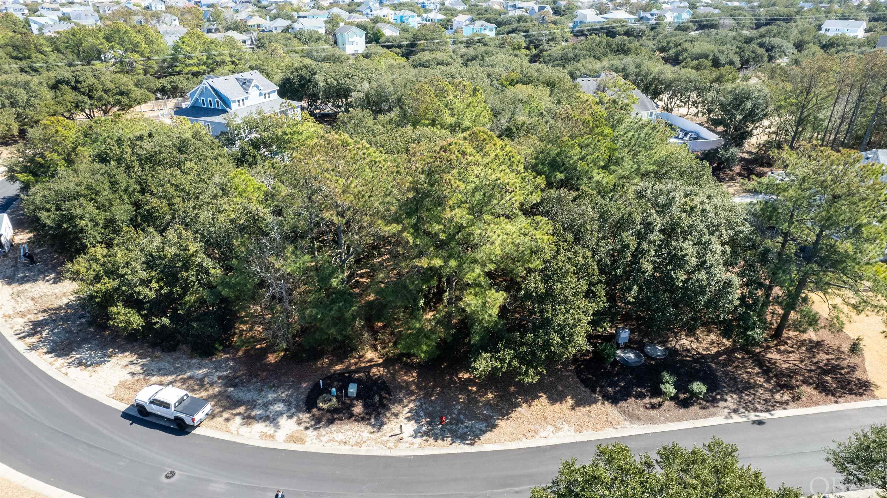 This picturesque homesite is located at the north end of The Currituck Club for the ultimate peace and quiet.  The location is close to the north community pool and just one lot off the sound front you may have a view of the sound and marsh from the upper level of your new home.  You do not want to miss this one. The Currituck Club is an exquisite resort community. It is the ideal location to build a primary residence, second home, or vacation rental with exceptional surrounding homes. Owners and guests have access to a wide array of amenities. There are a variety of stunning live oak trees on the lot.  This includes but is not limited to a private, gated community with a security guard to monitor those who enter the community 24 hours a day. There is a Trolley Service that runs seven days a week all summer. The fitness center is open seven days a week. There are many areas to enjoy various sporting activities around the fitness center including basketball courts, tennis and pickle-ball courts, a sand volleyball court, a shuffleboard court, and a bocce ball court. Not only are there awesome fitness amenities, but there are also 3 community pools! The main pool also has a tiki bar, a great socializing place! For the golfers in the group, there is an extraordinary 18-hole semi-private golf course designed by the legendary Rees Jones. Additionally, you will find a world class practice facility including a putting green, driving range and a bunker. It is a par 72 golf course that is fantastically maintained. Your future home would offer sweeping sound views. There is a restaurant available at the Hunt Club Tavern. Exceptional opportunity!  Survey and proposed site plan on file.
