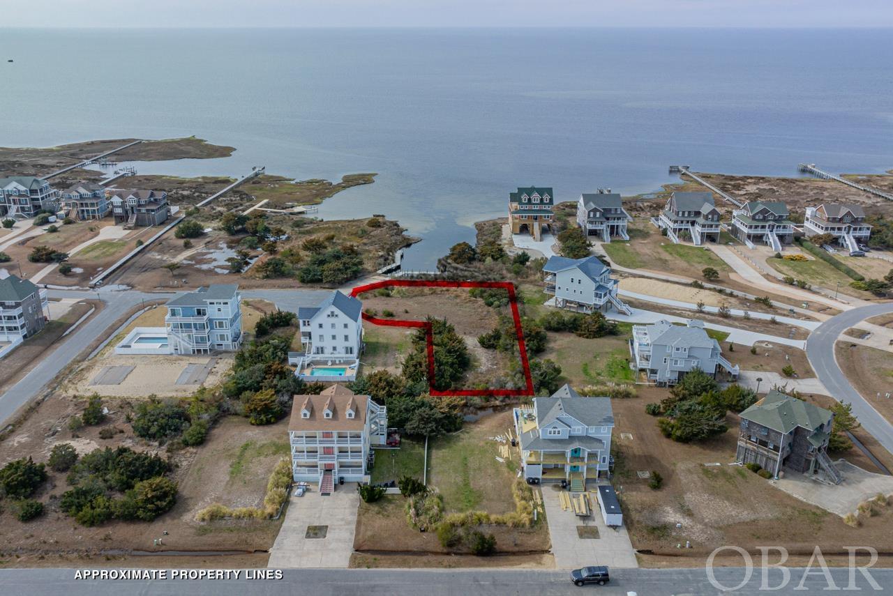 Embrace the rare opportunity to own a piece of paradise with this expansive 23,000 square foot lot, perfectly positioned in the heart of the prestigious Wind Over Waves community in Waves, NC. Recently enhanced with a new bulkhead, this prime real estate offers direct access to the mesmerizing Pamlico Sound, setting the stage for your dream waterfront home amidst luxury and breathtaking sunsets. Wind Over Waves is not just a location; it's a lifestyle choice, offering a resort-style soundfront community that is revered for its elegant homes and unbeatable views. The community itself boasts a suite of top-tier amenities designed to enrich your waterfront lifestyle. Enjoy exclusive access to a 100-foot community pier, ideal for kiteboarding, paddleboarding, or soaking in the panoramic sound views. The community boat ramp invites endless aquatic adventures directly from your doorstep, while the convenient sidewalk paralleling NC-12 makes exploring the Tri-Villages a breeze. Beach access is merely a short walk away, ensuring every day can be as active or relaxed as you desire. Located on the scenic Pamlico Sound, this lot is not only a gateway to serene waterfront living but also sits at the crossroads of adventure and recreation. Nearby attractions such as Pea Island National Wildlife Refuge, Bodie Island Lighthouse, and Oregon Inlet Marina cater to nature enthusiasts, history buffs, and anglers alike. The Salvo Day Use Area, within two miles, offers sound-front beaches, picnic spots, and a playground, making it an ideal spot for family outings. Moreover, the location serves as an ideal base from which to enjoy the Outer Banks' stunning sunsets, sound views, and the natural beauty of Hatteras Island. This lot represents an unparalleled opportunity to custom-build your dream waterfront estate in one of the most coveted communities on Hatteras Island. Whether you envision a peaceful retreat or rental home, Wind Over Waves offers the perfect backdrop. Seize the chance to experience the best of coastal living and make your waterfront dream a vivid reality in Wind Over Waves.