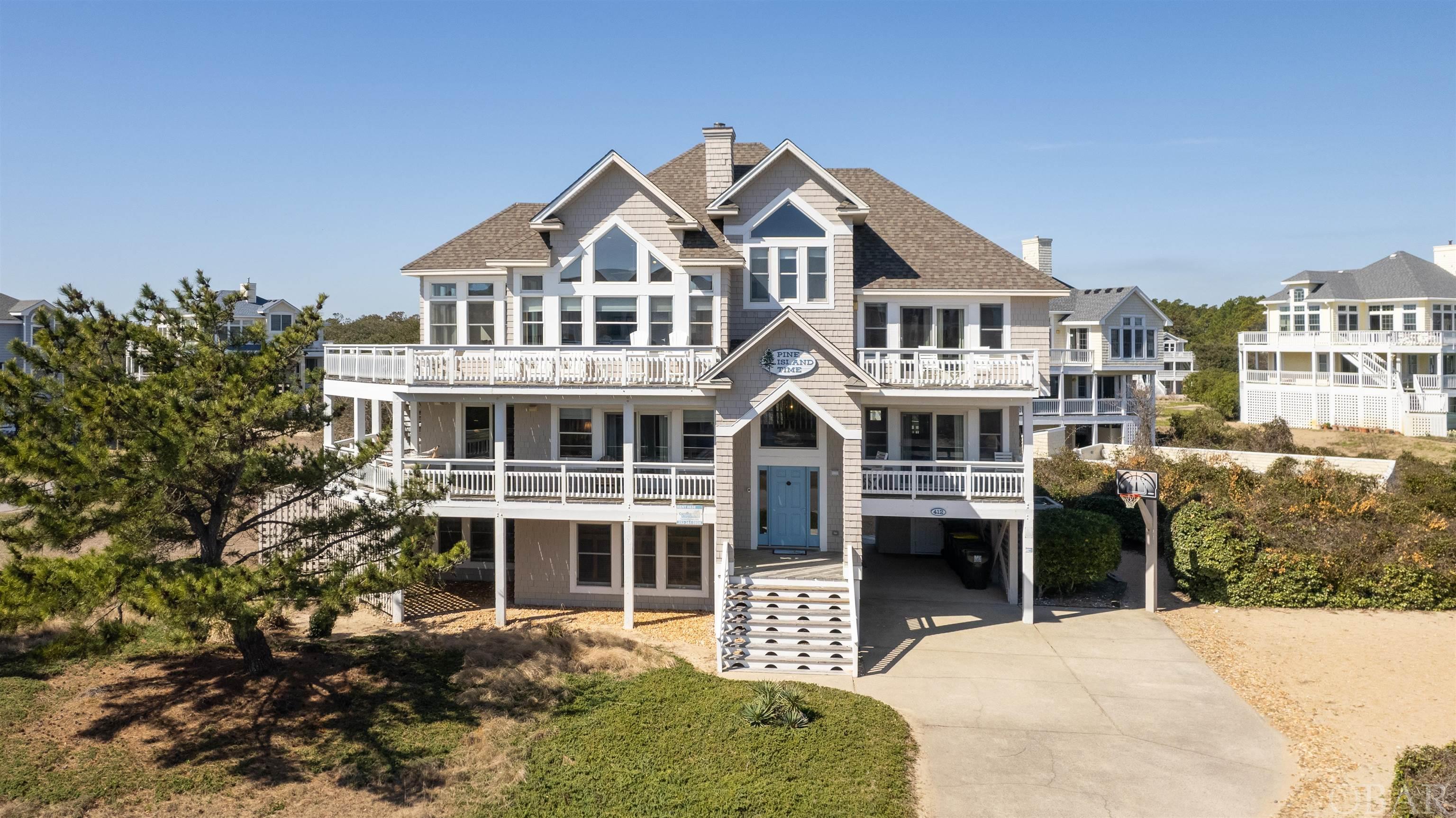 Welcome to 412 Deep Neck Road, a stunning semi-oceanfront retreat located in the renowned Pine Island community of Corolla, NC. Boasting views of the ocean, direct beach access steps away, a spacious corner parcel with added privacy, and gracious interior and exterior living spaces, this is a home and location you don't want to miss. In addition to 5 bedrooms, 5.5 baths, an elevator, laundry room with two washers and dryers, and a volleyball court, the home features a second level den, game room with pool/ping pong table, high top seating, and wet bar for added entertainment. An open concept living room with surrounding windows, hardwood floors, and a gas fireplace, both island and dining seating, a sunroom, ship's watch, and kitchen with dual stainless appliances, a standalone ice maker, and granite countertops was thoughtfully designed for hosting large groups of friends and family. A private heated pool and spa, two outdoor showers, a fish cleaning station, and exterior 1/2 bath, offers the perfect set up for comfort and convenience after days spent on the wide white sandy beaches of Corolla. While offering a peaceful and secluded ambiance from all the Island's action, the drive or bike ride to town takes less than 10 minutes where you can indulge in a number of terrific local shops, restaurants, and attractions to include the Historic Whalehead Club and Currituck Beach Lighthouse. Enjoy the extensive community amenity list offered in Pine Island from the community pool, playground, tennis and basketball courts, and health club for an additional fee.