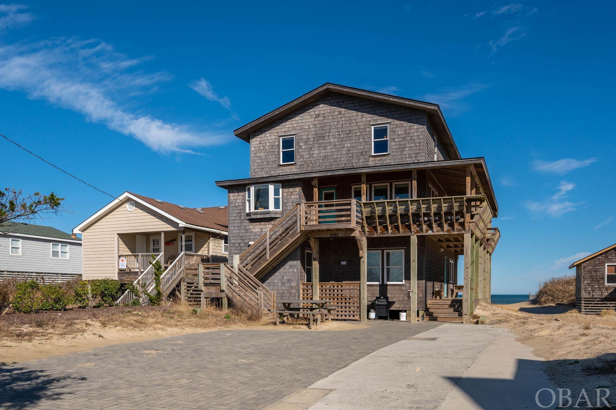 OVER $160,000 in GROSS RENTS IN 2023! This indeed is a very rare opportunity for you to own in the unpainted aristocracy of Cottage Row in Nags Head. Listed on the National Register of Historic Places in the Old Nags Head District, this 7-bedroom, 6 full-bath home has been thoughtfully and intentionally upgraded without sacrificing any of its original charms. The traditional Nags Head Cottage design with wrap-around porches and abundant windows affords dazzling ocean views to the east and breathtaking sunsets over Jockey's Ridge to the west. Enjoy traditional style living on the open-concept main level with incredible views of the Atlantic and a nostalgic fireplace that beckons cozy, family gatherings. On the top level, you'll find four spacious bedrooms, two with en-suite baths and access to open decks for private sun tanning or ocean gazing, and two with a shared bath and incredible views of Jockey's Ridge. In 2019, three additional bedrooms and a den completed on the lower level with wet bar were added to this home. Outdoors you'll discover easy access to the beach, more seating areas and an outdoor shower. This property offers so much with its modern amenities while retaining its original Nags Head design. It's definitely a must-see!