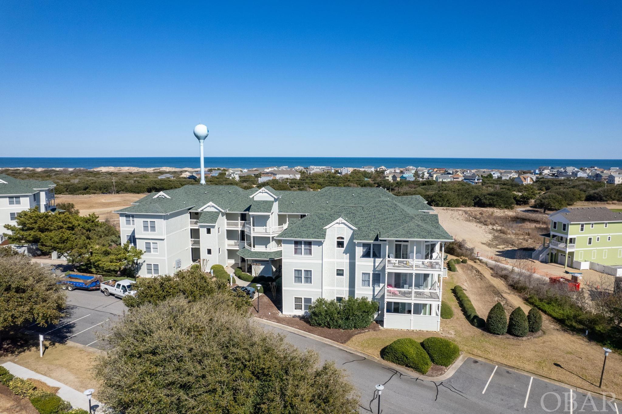 Pristine Villa perched atop one of the highest elevations in The Club. The beautifully maintained and spacious 2 bedroom corner unit home is located within the sought after community of Windswept Ridge Villas in the Currituck Club. Ample light pours in from 2 outdoor patios from this 2nd floor unit. "Postcard Perfect" is perfectly positioned to provide views of the beautiful blue waters of the Atlantic Ocean and vistas of the Rees Jones designed golf course.  The home offers newer living room furniture, curtains, flat screen tv's, décor, mattresses, bedding and interior paint. 2018-2019 new interior air handler (RA Hoy). 2022 New dishwasher. 2024 New refrigerator with ice maker. With ample-sized bedrooms and an open floor plan, the home lives large! The amenity-rich community of the Currituck Club provides enhanced fun & entertainment: Clubhouse, several private community pools, tennis courts, fitness center, playground and beach trolley services! With elevator serving all levels of the building, this villa checks all the boxes! No detail overlooked in this impressive community and property. Recent updates to the building include: new roof in 2018, full exterior paint and siding repairs in 2023, and new gutters in 2023.
