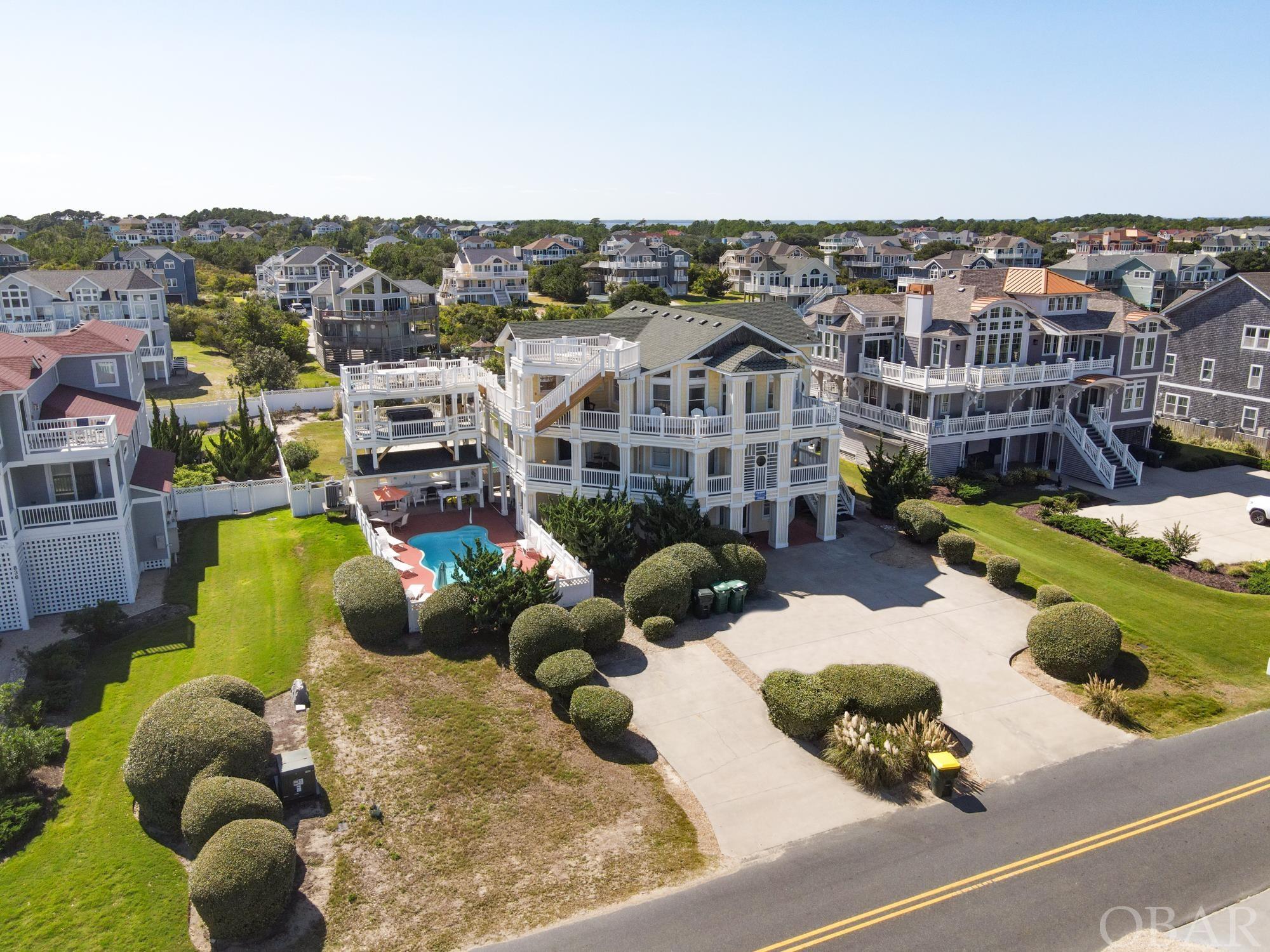 Welcome to “Sunlight,” your dream coastal retreat in the popular Whalehead Community of Corolla with over $200k on the books for 2024. This remarkable semi-oceanfront property boasts an incredible 9 bedrooms and 8 bathrooms, making it the perfect haven for large families and groups seeking the ultimate Outer Banks experience. As you approach this stunning home, you will immediately notice the tasteful upgrades that enhance its curb appeal and functionality. The recently installed new decking on the top deck offers panoramic views of the Atlantic Ocean, allowing you to savor breathtaking sunrises and unwind with the soothing sound of the waves. The northeast side of the home originally had stone siding that was removed and was recently replaced with LP Smart Siding. Set up as a reverse floor plan, on the top level of the home, you will find a great room, with high ceilings and many ocean-facing windows to allow natural light to fill the space. The large kitchen comes equipped with a new cooktop and granite countertops. There is one bedroom on the top level that has new flooring with access to the wrap-around decks. The middle level also has all-new flooring throughout the 5 bedrooms. The ground level comes equipped with a rec room and the remaining three bedrooms. This area flows out seamlessly to the pool area. The pool area is surrounded by 3 levels of decking with a tiki bar on the bottom and a hot tub in the middle. Schedule your showing today and enjoy walking into a summer full of rental income.