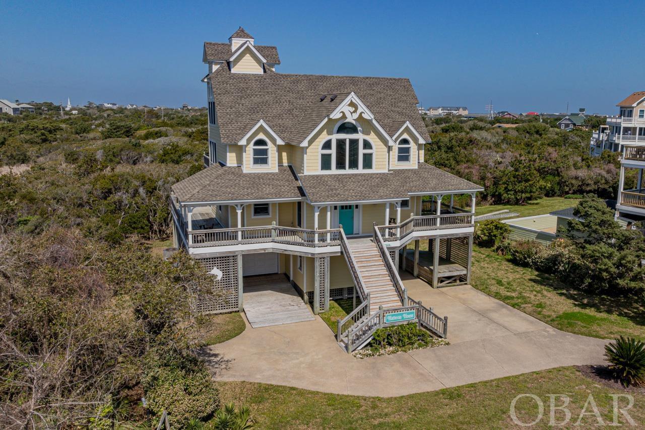 Welcome to a breathtakingly renovated oasis nestled within the private, oceanfront community of Hatteras by the Sea. This extraordinary 4-bedroom, 3-bathroom home, meticulously transformed in 2018, features a new roof, siding, and premium Anderson windows and sliders, establishing it as a paragon of modern coastal living. Situated on a spacious lot that borders a coastal nature reserve, it presents an unparalleled living experience in the quaint, charming fishing village of Hatteras.The elegance of this home is immediately noticeable with its custom interior rod railing, adding a sophisticated touch throughout. The welcoming foyer opens to three beautifully appointed bedrooms on the lower level, including a lavish king ensuite, an additional king bedroom, and a queen bedroom sharing a stylish hallway bathroom. Ascending to the open-concept top floor reveals a culinary haven, featuring a kitchen outfitted with soft-close cabinetry, ceramic tile floors, quartz countertops, and top-of-the-line stainless steel appliances, including an oversized Frigidaire refrigerator. The living space is extended to a king bedroom with an attached bathroom and a versatile game room, perfect for hosting or quiet nights in. Luxurious Cortec LVP flooring throughout ensures elegance and durability. A spiral staircase invites you to a third-floor loft, providing a serene escape with a sectional sofa and bookshelves.The outdoor living spaces are equally impressive, tailored for the ultimate beach lifestyle. An elevated garage and carport cater to the included golf cart, affirming the golf cart-friendly allure of Hatteras Village. Multiple decks, an outdoor shower, and ample storage space with a secondary fridge elevate the convenience and enjoyment of your seaside retreat. Owning in Hatteras by the Sea is about embracing a coveted lifestyle. With deeded beach access and the community pool a short walk away, bordered by pristine marshes and the sweeping ocean, your days can be as relaxing or adventurous as you desire. This idyllic setting is also moments away from the heart of Hatteras Village, where shopping, waterfront dining, and fishing are part of the daily rhythm. This home not only offers a luxurious living space but also comes complete with a golf cart, making it a truly turnkey solution for your dream of coastal living. Immerse yourself in the beauty and serenity of Hatteras by the Sea, where your beachside sanctuary awaits.