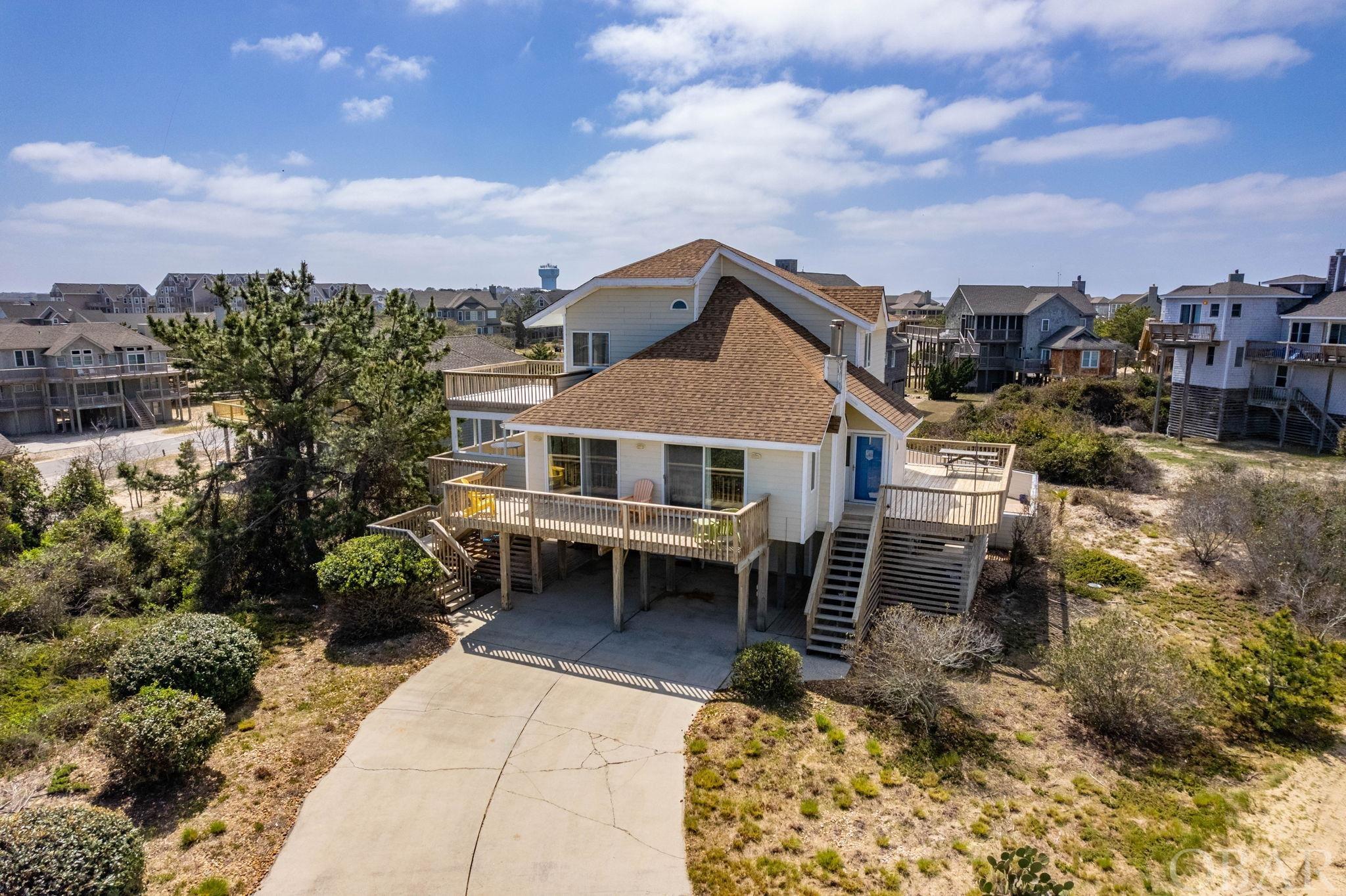 Location is everything and more with this one! INCREDIBLE VIEWS. The high elevation (28-30 feet) at the top of the dune gives this property commanding views of the ocean and Research Pier property.  Sandy Ridge is a small community with private beach access. Although rentals are allowed, most of the homes are used exclusively by the owners.    The 15,000 s.f. site is 145 feet wide and 103 feet deep. This will allow for a home with exceptional curb appeal and architectural significance.    The current home has been used as a second home for years. It has just over 2000 s.f. with four bedrooms, three full baths, an open concept kitchen/dining living room, a lovely, covered porch, and another common area/media room with a bath on this ground level as well. The main living area is perfect for taking in the views and has a great feel with a vaulted ceiling. The porch adjacent to the kitchen enjoys sublime summer breeze! On the top floor, 2 bedrooms share one bath. The top deck has even better views of the ocean and sound. On the main floor there are also 2 bedrooms and one bath.  Outside there is a 14 x 34 heated pool with a very beachy feel!  This home is great as it is, or you could expand the kitchen and add baths! This site is so incredible that it is easy to envision a new home here too!  All of the lots to the east of this home are developed. There is no vacant lot between 116 and 118 Sandy Ridge so those great views of the ocean and pier should remain. There is a community pool that is open in the summer. There are reasonable covenants and architectural review in Sandy Ridge. With just 170 yards to the beach access, you will not find a home closer to the beach with better views and elevation!