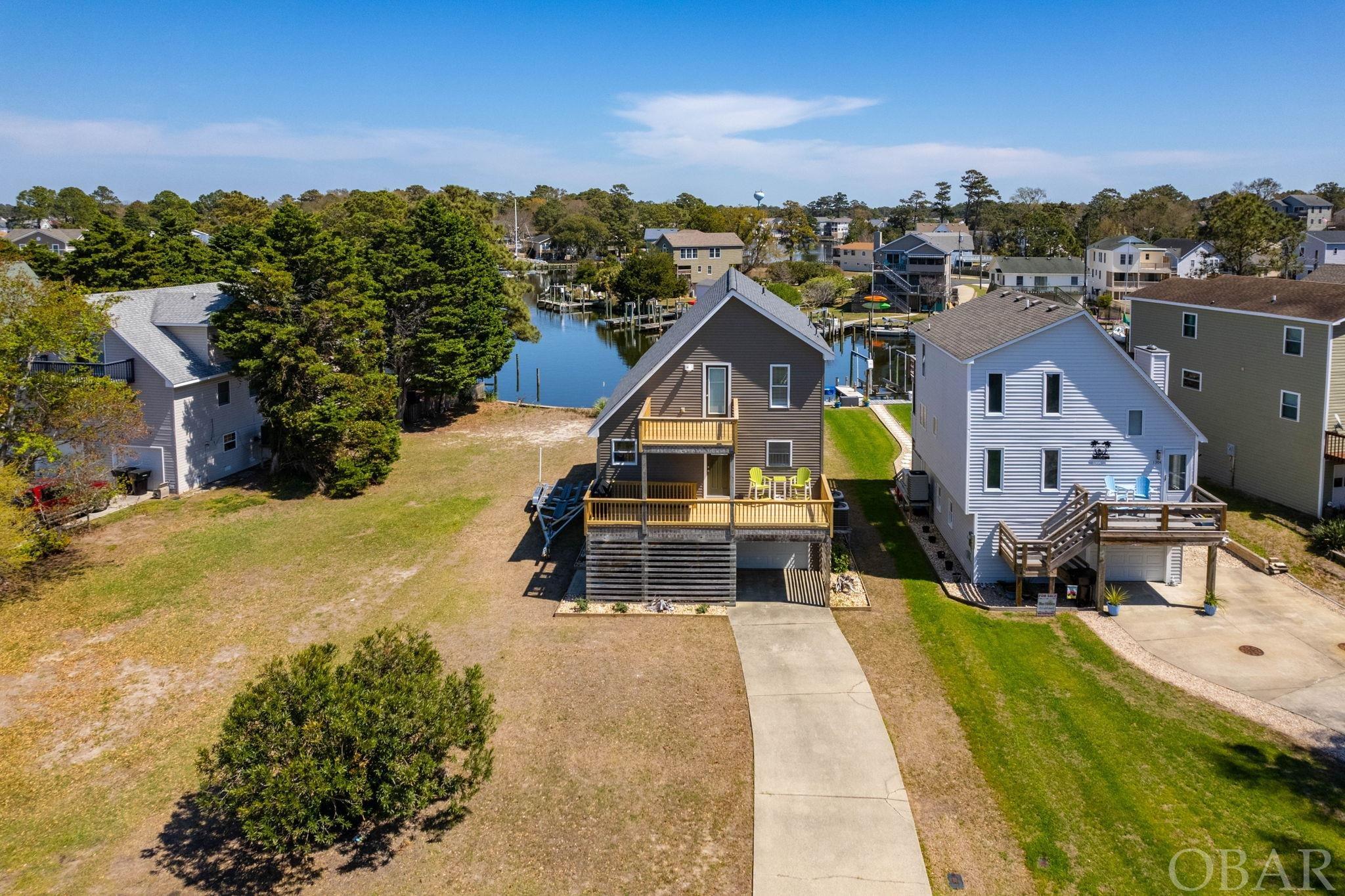**MOVE IN READY** The best of both worlds for Water Views and Sunset Views. This Waterfront property faces east on the canal side with 2 story sun decks and faces west towards the Albemarle Sound with 2 story sun decks as well. So take your pick and sit back to relax and enjoy the views. Top Quality Renovations have been made throughout by the current seller and are too numerous to list. The attention to detail shows. Ask for the complete renovation list or view in the associated docs. You will not be disappointed with this updated and renovated 3 bedroom 2 bath waterfront home. The large ground floor garage and storage area has ample room for all your watersports equipment and beach gear storage. Plus, there is a dry entry as well to make coming home on those rainy days a little easier. Please note, water side deck renovations are still in progress with new railings and decking being installed.  Located in a 24 hour 7 day a week gated waterfront boating community with numerous amenities. The Community Amenities are: waterfront outdoor pool, covered pavilion, pool side tables with umbrellas, sun deck, pool lounge chairs, clubhouse, sound side beach with park, playground, bath house, boat ramp, marina, docks, dog park, and basketball court. Nearby, is a community favorite secret sound side beach for finding great pieces of driftwood. Call to schedule your showing of this beauty. Sold Furnished with a few exclusions. See the Associated Documents for Information. The boat shown on lift is also available for sale, but not included. Heated Sq. Ft. Measurements are for information purposes and to be confirmed by buyers agent