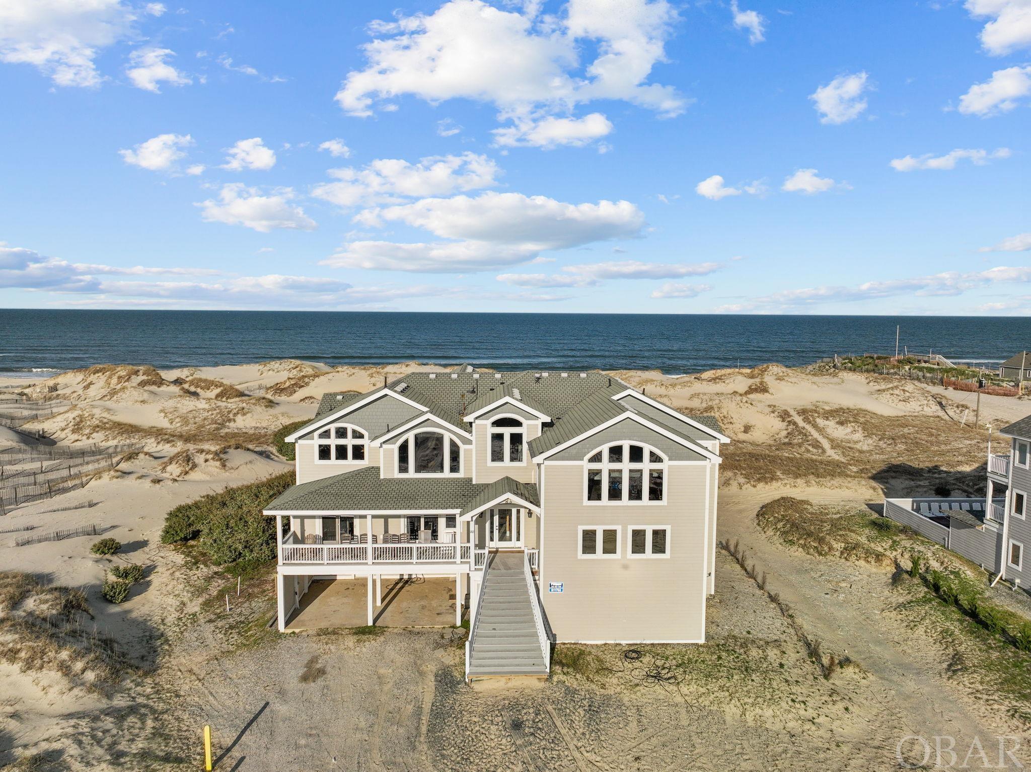 Indulge in the serene beauty of nature and sweeping ocean views in this grand oceanfront retreat situated on a 3-acre lot in the coveted 4x4 section of Corolla.  With almost 8000 square feet of living space, this home is meticulously designed to comfortably accommodate large gatherings while offering all the amenities required for a successful investment property. The top floor boasts an open and spacious layout, adorned with spectacular ocean views that you'll never tire of enjoying. The expansive kitchen is a chef's dream, equipped with three dishwashers, two microwaves, three ovens, two range tops, two sets of sinks, and an ice machine! Whether preparing meals for family and friends or hosting a beachfront feast, the ample dining space ensures everyone has a place at the table. The Great Room features a massive new sectional sofa, perfect for unwinding while soaking in the breathtaking ocean vistas. Entertainment abounds within this luxurious retreat. Enjoy movie nights in the state-of-the-art theater room, challenge friends to games in the two spacious game rooms, or find solace in the mid-level den/office. Outside, a private oceanfront pool and two hot tubs beckon relaxation, while multiple decks offer idyllic spots for savoring sunrises or stargazing. The ground level game room is a hub of activity, opening out to the oceanfront pool area and equipped with a convenient kitchenette, pool table, ping pong table, and foosball table. It's likely this space inspired the cottage name "Straight on 'Til Morning" where endless fun and memories await! Each of the twelve bedrooms offers spacious comfort and features en-suite baths, with some boasting decks offering ocean and pool views. This home truly offers all the comforts and conveniences expected for an amazing investment opportunity in the sought-after 4x4 beaches of Corolla, renowned for its majestic wild horses. Don't miss this unparalleled opportunity to own a piece of paradise where luxury meets coastal charm. Schedule a viewing today and experience the epitome of beachfront living in Corolla's pristine 4x4 beaches. Recent improvements include: LVP flooring in Game Room (2024), sound system updated to an integrated Sonos System throughout the home (2024), new Deck/Pool furniture (2023/2024), new manifold and pump equipment for well water, new sensors and piping (2023), hot water heater (2022), one HVAC replaced (2022), entire interior of home painted (2021). Pool upgrades - filter head, new 1 horsepower pump and misc plumbing parts estimated at $4800 scheduled to be completed April/May 2024