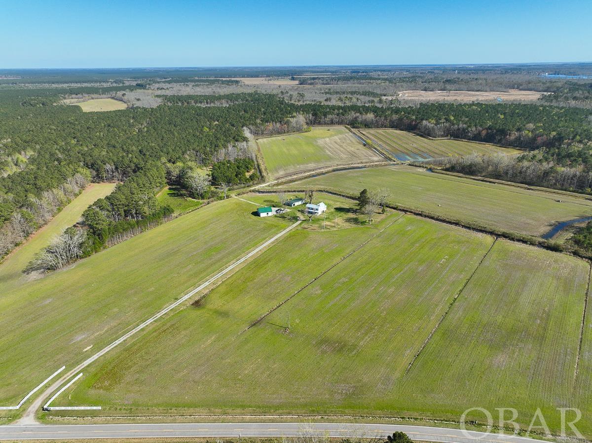 From a well-rounded aspect, this 280 acre offering is truly special and wildly unique in the marketplace. It's located in the River Neck section of Tyrrell county with 1800 feet of frontage at the western end of Soundside Road. The gated entrance to the property is 4.1 miles north of Highway 64 in Columbia North Carolina. Columbia is a small coastal river town on the Albemarle Peninsula and Highway 64 is the main transportation artery between Raleigh, 2.5 hours to the west, and the Outer Banks, 45 minutes to the east. Some other common destinations from this property would be the quaint coastal town of Edenton North Carolina at under 40 minutes and both Chesapeake Virginia and Greenville North Carolina are an hour and a 1/2.   At the end of the 750 foot long driveway are 3 structures highlighted by the 1901 farmhouse that was restored by the previous owners. The configuration this cool country abode is 2 bedrooms and one full bathroom upstairs (the septic permit allows for the construction of a third bedroom). Downstairs, you'll find another full bathroom, laundry room, a boot room and a flowing living/dining/kitchen area. The current owners converted a screened-in back porch into a fully enclosed sunroom, which overlooks the 3 duck impoundments. This classic country farmhouse wouldn't be complete without a metal roof and covered front and side porches. The owners are in the process of moving and pictures of the home will be posted once they have finished. At 2048 Sq ft, it's plenty adequate for a full-time residence in the country for a small family, or for an incredibly cool hunting camp or weekend get away. Also on the homesite is an older restored livestock barn and a newer 2 story garage/barn. Both are complete with matching barn doors and provide ample room for tractor/equipment, vehicle, boat, hunting gear and implement storage.   This place is a wildlife manager's dream property. With 59 acres of farmland, multiple food plots, bottomland hardwood swamps and mature pine timberland. 33 acres of the farmland have been converted into diked waterfowl impoundments, all 3 of which are serviced by one centrally located well and electric pump. The pines are certainly merchantable but there has been no cruise performed or value established. Although there are ongoing wildlife management practices in place, the full wildlife potential here is far from realized.  The current owner and his family have made countless irreplaceable memories on this property since purchasing in 2010. Since that time, the owner has experienced the joy of seeing his sons each harvest their first deer, first duck, first turkey and first bear. There are plenty more of each and it's time for the next owner and the next generation to experience this coastal North Carolina gem. This incredible property is shown by appointment only to qualified buyers.