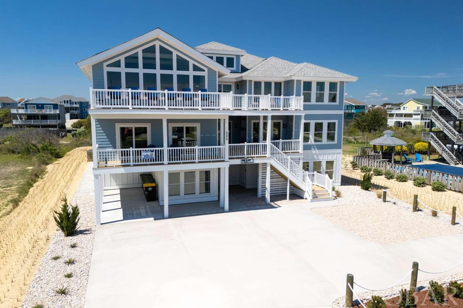 This brand-new semi-oceanfront estate in popular Whalehead Beach is sure to impress. Designed and built by Finch & Company, this fully furnished 12-bedroom home features spectacular unobstructed ocean views, and each bedroom includes its own private, custom tiled bathroom. With over 7600 square feet, there is an abundance of gathering spaces and oversized bedrooms for large groups to spread out and enjoy themselves, along with an elevator to easily navigate throughout the home. The layout features three spacious, coastal-inspired levels, professionally designed for both comfort and entertainment. The top floor offers an open concept with cathedral ceilings and large picture windows, bringing in an abundance of natural light and offering sweeping ocean views. The spacious gourmet kitchen includes a large center island, double ovens, 6 burner professional cooktop, two dishwashers and refrigerators, quartz counters, custom shaker cabinets, and 15ft custom dining table with seating for 18. The living area includes custom built bench seating, conversation seating area for 4, and extra-large sectional sofa, perfect for gathering around the large screen TV or taking in the amazing views from the large picture windows. Rounding out the top floor includes front and back decks for alfresco dining, separate sitting area, and three master ensuites. The mid-level includes six well appointed ensuite bedrooms all of which were designed for space and comfort, including an oversized custom built bunk room with four twin and four full sized bunks. A large media room with wet bar, private office, and plenty of front and back deck seating round out the mid-level. The ground floor offers a nicely sized theater room with Italian leather seats, 85-inch TV, and Sonos sound system. The rec room includes a pool table, shuffleboard table, stand up arcade with 10,000 games, 75-inch TV, conversation seating, wet bar, professional ice maker, and full-sized refrigerator. There is also a custom installed Sonos sound system inside and out which operates easily from an app on your phone. Outside amenities abound with a heated salt water pool with sun shelf and in-pool bar stools, perfect for staying cool on those warm summer days. Two large covered cabanas include bar and lounge seating, perfect for keeping the party going all day long. Enhancing your poolside experience includes a large flat-screen TV, outdoor speakers, hot tub, ping pong table, cornhole boards, and outdoor shower. The exterior was professionally landscaped with drip irrigation and easy to maintain plants ensuring the grounds look great with minimal supervision. All this while located in an X flood zone. Welcome Home.