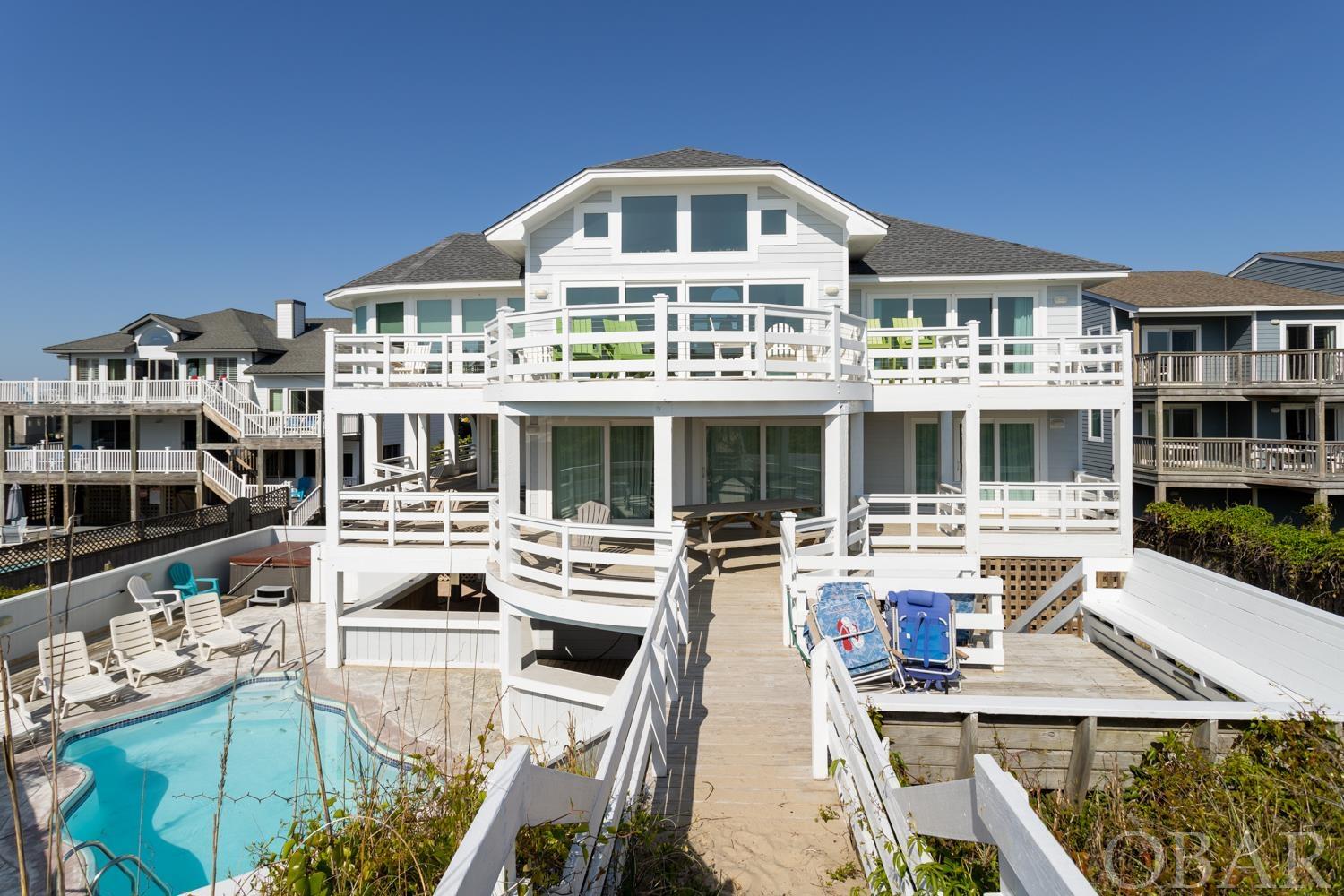 You'll be "Over The Moon" for this incredible updated oceanfront home in Duck with breathtaking ocean views and tons of natural light! A proven rental producer, this home has all of the most sought-after amenities including an elevator, private pool, rec room, and theater room. With over $220k of rental income in 2024 and rental projections as high as $260,000, this house makes for the ideal investment property. Set up in a reverse floor plan, the top level has the “wow factor" with panoramic ocean views from every angle. The open floor plan flows seamlessly between the great room, kitchen, and dining area, and up to a west-facing ship's watch. The large upstairs primary bedroom has deck access and views of the ocean from bed. The middle level comes equipped with four bedrooms, all of which have deck access and two that are ensuite. The ground level is full of fun for everyone to enjoy rain or shine. A large rec room with pool table and foosball connects to the fully equipped theater room with tiered seating. Outside is your own little private oasis with a pool, hot tub, and plenty of room to lounge whether you prefer the sun or the shade. Take a few steps over the beach walkway right to the beach. In the last four years, significant updates to the home have been completed such as two new HVAC systems, new flooring throughout, interior/exterior paint, new high-end mattresses and furniture, a new roof, a new outdoor bar, and new outdoor furniture, just to name a few. Pre-listing home inspection on file. Don’t let this one get away!
