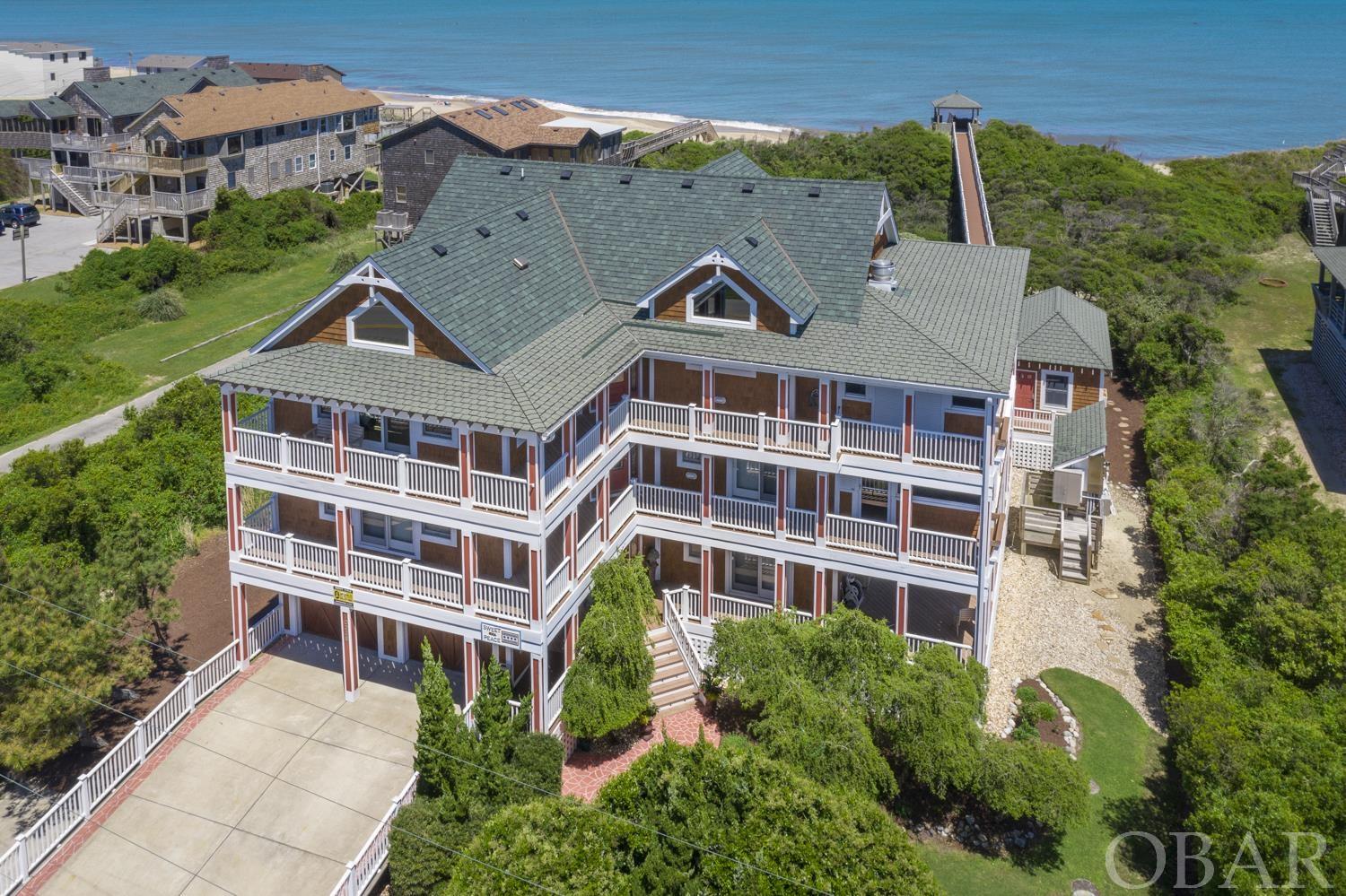 Surrounded by a beautifully landscaped yard, and referenced by Dare County Tax records as a: "Modern Oceanfront Estate."... it would take pages to describe just how incredible this 8 bedroom, 8 bath, oceanfront home is. The open living area with a vaulted ceiling is perfect for visiting with family and friends. Hoping for an updated kitchen that's tastefully designed? This house has it! Quartz countertops, a substantial island, sub-zero refrigerator, gas range with hood and plenty of storage. Step out from the lovely dining area into a large screened-in porch with a built-in gas grill with an exhaust hood and an additional table for dining. From the porch you can see the sound to the west and the ocean to the east. While looking out at the ocean (from one of the multiple decks), your eyes will find the oversized pool (28 x 46) that includes a hot tub, kiddie pool and baja shelf for relaxing in lounge chairs. There is also an outdoor brick fireplace to enjoy for the chilly beach evenings. For those who like to work-out before hitting the beach, no problem...there's an out building with exercise equipment. Other amenities include a theatre room, a hot tub located on the mid-level deck, a recreation room on the ground floor and multiple large screen TV's throughout the house. If you're stuck doing laundry, you can be done in no time as there are 3 (yes, 3!) sets of washers and dryers. The bedrooms are spacious and the bathrooms are elegant. Other property details include an elevator to all 3 levels, mechanical shades, ice machine, and even a boardwalk to your very own gazebo that leads directly to the beach! This property is only 1.8 miles from the Hatteras National Seashore. Let your dreams begin now!