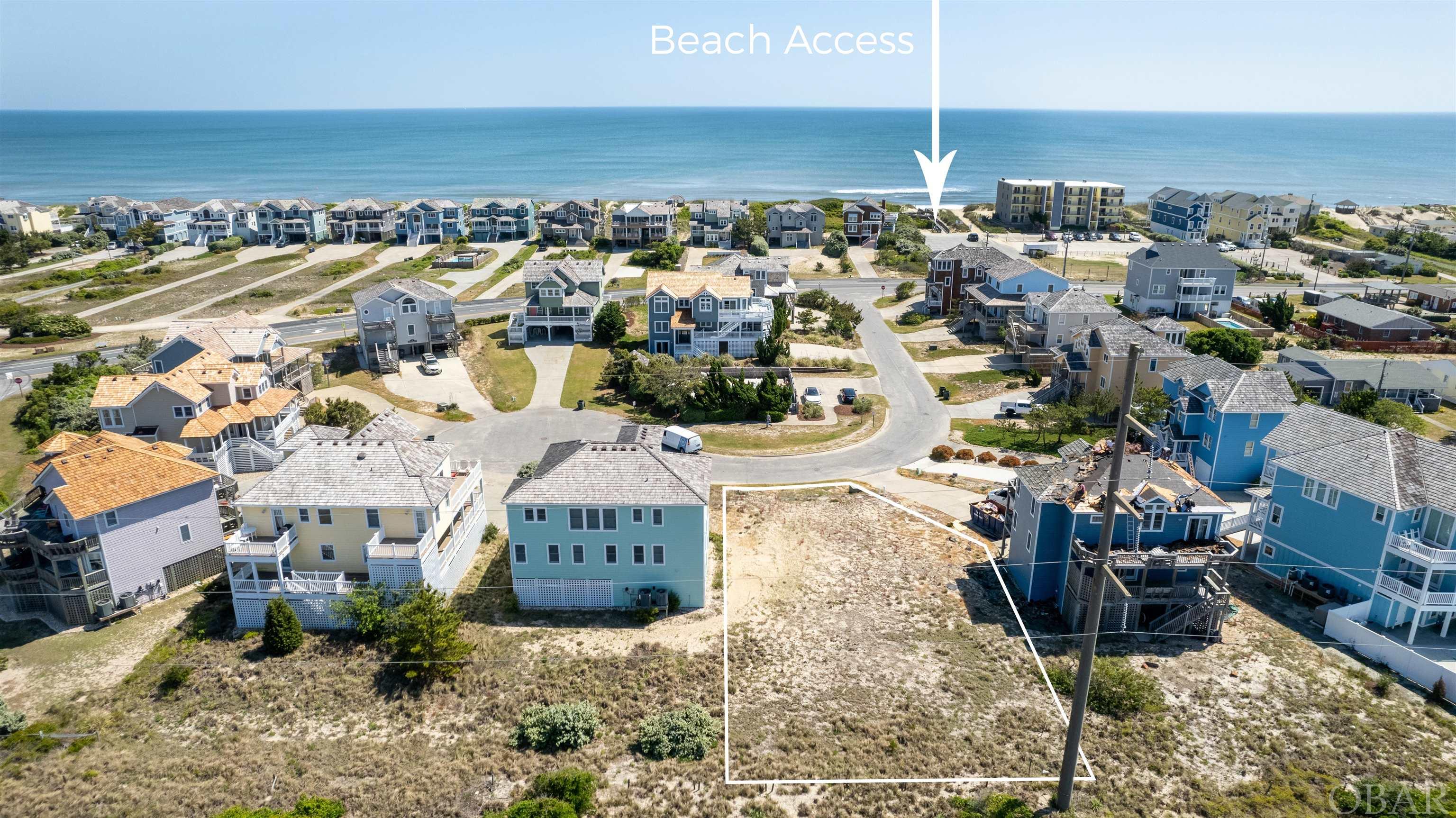 This is an incredible and rare opportunity to own the last vacant lot in Oceanwatch! It is located just steps to the community pool or beach access.  High elevation of the property should provide a view of the ocean and sound and the golf course.  The location is also in the heart of The Village at Nags Head.  The private community pool located directly across the street is for the small neighborhood of Oceanwatch only. Unlike most areas of the Outer Banks, The Village at Nags Head connects to the community septic system, allowing more lot coverage without worrying about installing a septic system.  The Village at Nags Head is a private ocean-to-sound golf course community; enjoy two private sound front accesses with piers, a gazebo, swings, a boat ramp, and more. Hop on the Village Shuttle for a ride to the ocean beach access with a bathhouse and dune top gazebo. Optional membership to The Village Beach Club with Olympic-sized oceanfront pool, beach equipment rental, clubhouse snack, and beverage bar. The Village At Nags Head is a resort community and the only one in Nags Head. The location is unbeatable, within a short walk or drive to many shopping, dining, and entertainment options.  There is something for the whole family to enjoy.